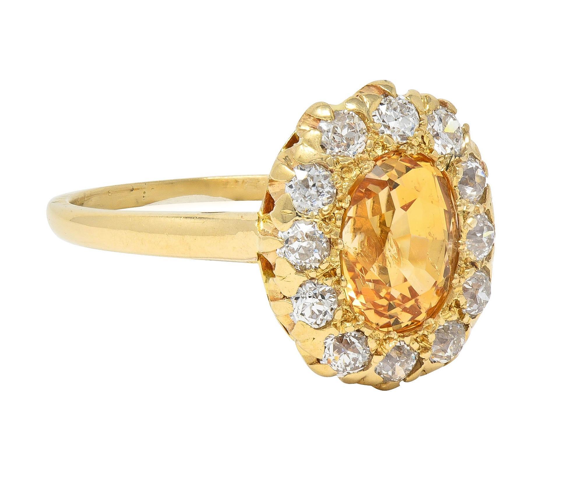 Centering an oval cut sapphire weighing approximately 2.49 carats 
Transparent medium orangey yellow in color - bead set 
With a halo surround of old European cut diamonds
Weighing approximately 0.72 carat total 
G/H color with SI1 clarity - prong