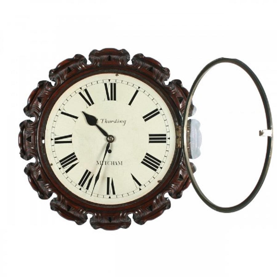 A Victorian fusee works circular wall clock in a carved walnut frame.

The clock has an eight day fusee movement with a white dial, Roman numerals and the name 'M Thursting Mitcham' painted on the dial.

The glazed door has a brass bezel and the