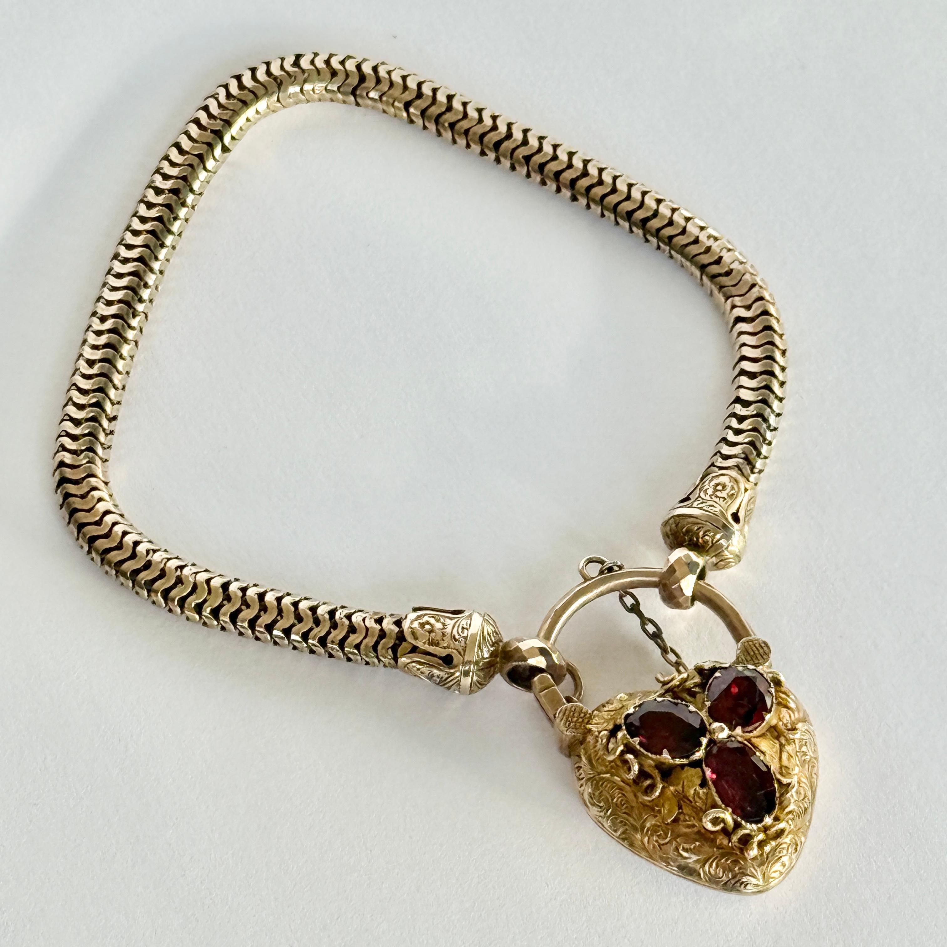 This bracelet is modelled in 15ct gold. The bracelet is fastened using a heart padlock which is super detailed and set with garnet. The back of the heart has a locket. Comes in original fixed box.

Length: 21cm
Chain Width: 5.5mm
Heart Dimensions: