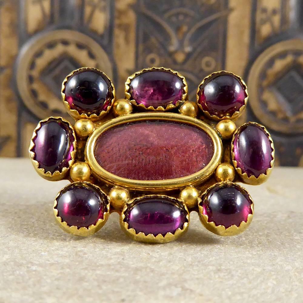 This mid Victorian brooch has been set in 15ct yellow gold. Featuring eight cabochon garnets surrounding a locket compartment, it is a wonderful antique piece.

Make this piece your own by featuring your own image or fabric in the locket compartment