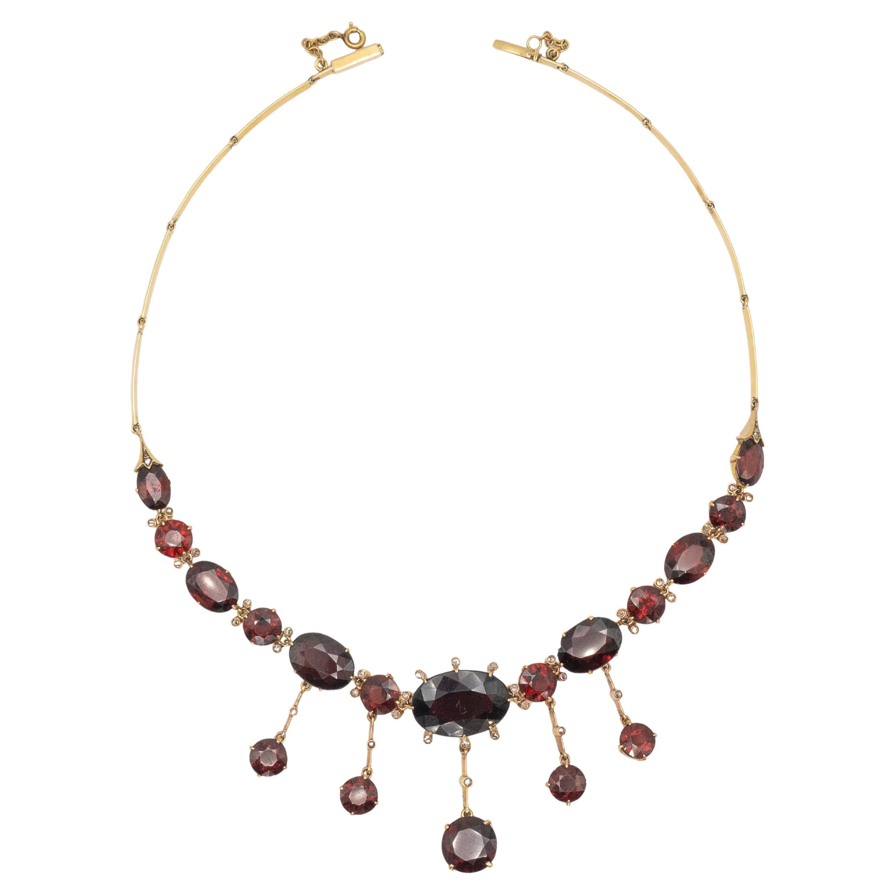 An exceptional antique necklace from the 19th century, finely crafted in 14K yellow gold and set with approximately over 70 carats of richly hued garnets. The design features a graduated arrangement of oval and round-cut garnets, with a striking
