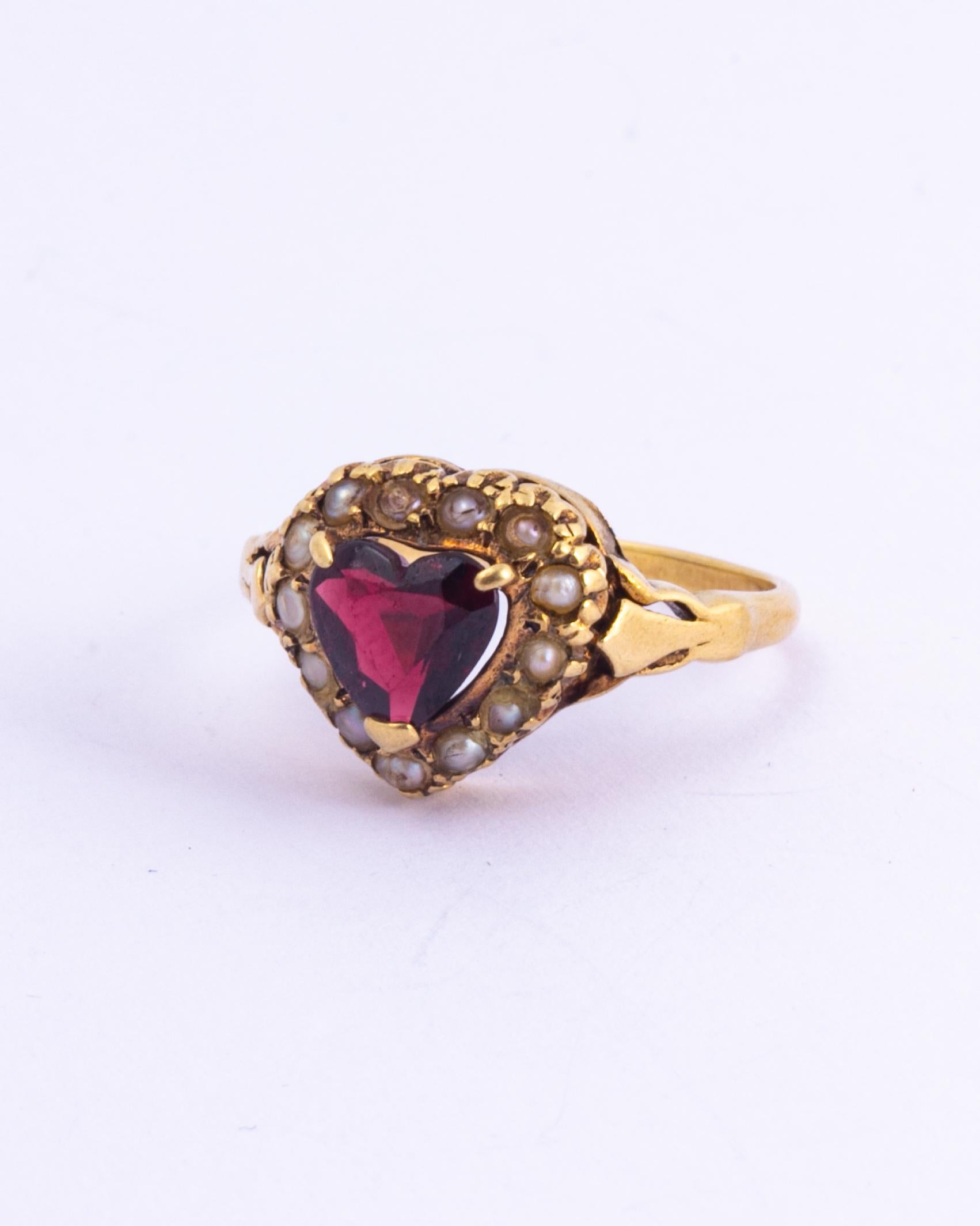 This stunning ring holds the most gorgeous red garnet in the shape of a heart. Surrounding this lovely stone is a halo of sweet pearls. The gallery is decorative and this ring also has moulded shoulders. 

Ring Size: N 1/2 or 7
Heart Dimensions: