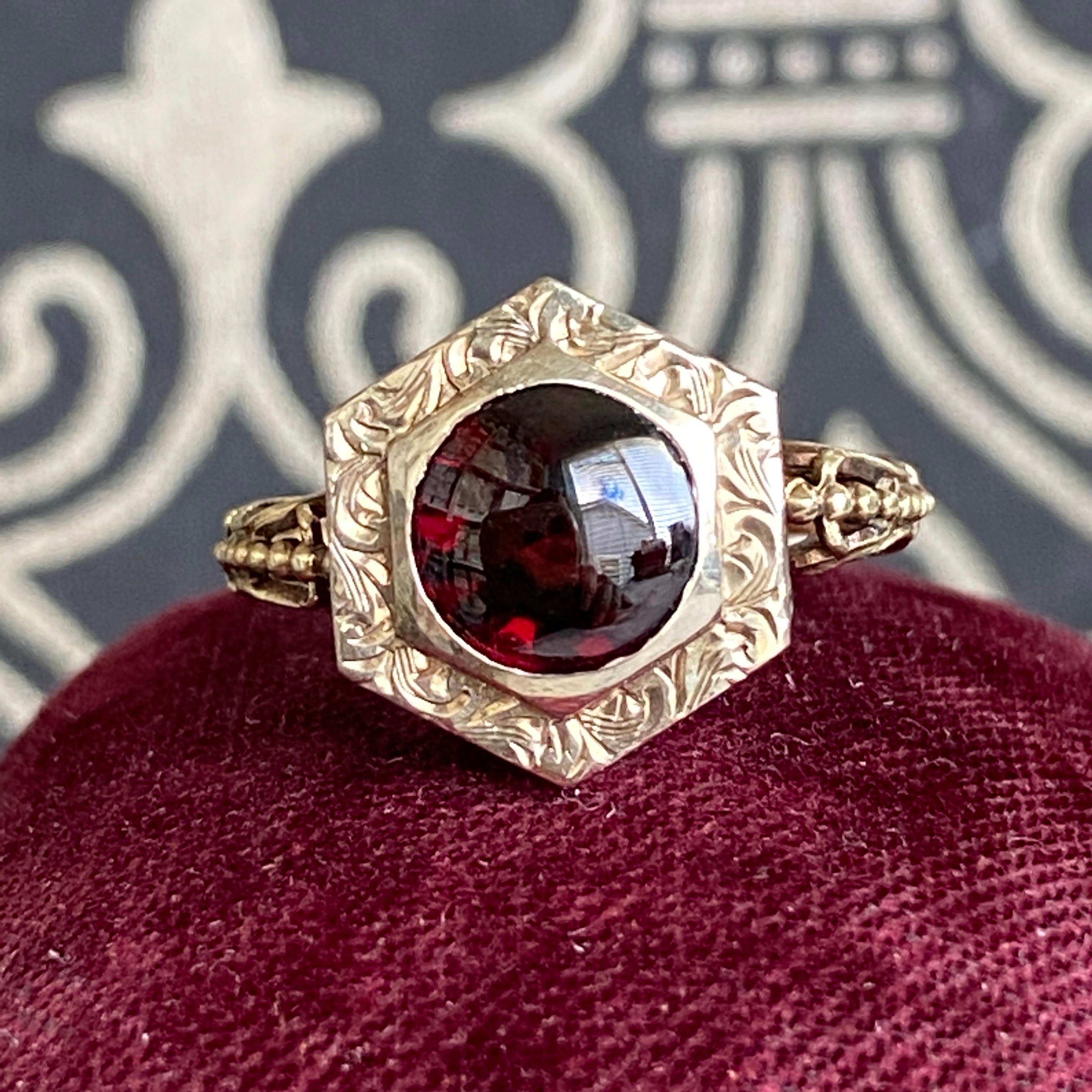 Details: 
A beautiful garnet ring from the Victorian Era (ca 1900's) era. This lovely ring is crafted in 14K yellow gold. The cabochon garnet measures 6.75mm round. The engraving on the sides of the setting is sweetly detailed.

Measurements:
Ring