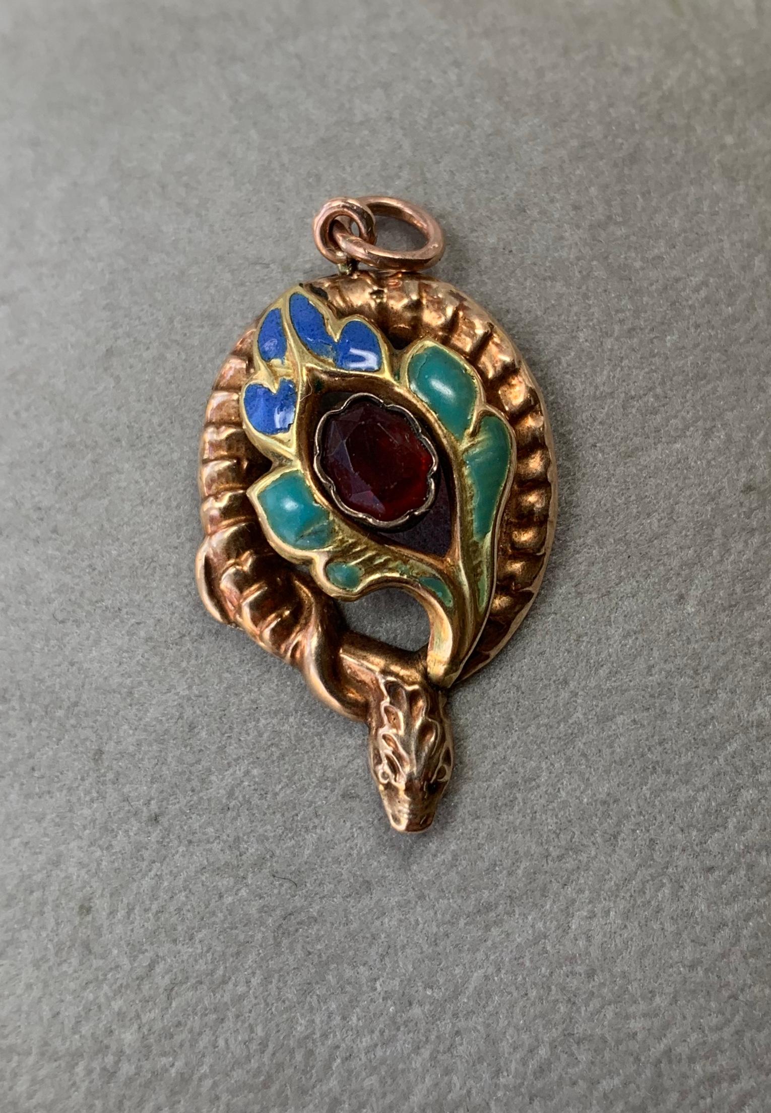 Indulge in a very rare antique Victorian Snake Pendant depicting a snake or serpent wrapped around a flower with a Bohemian Garnet center and lovely enamel adornment.  The snake pendant is beautifully created in 10 Karat Gold.  The snake is coiled