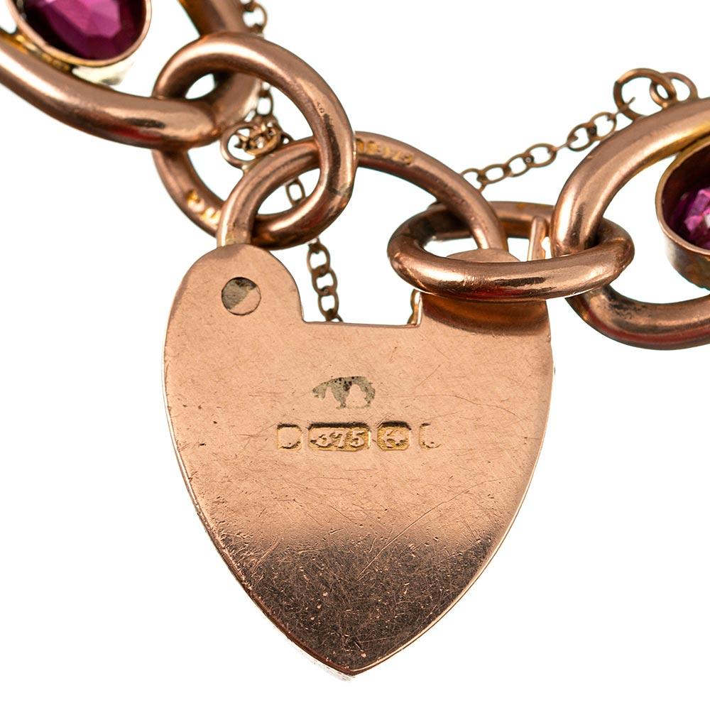 9 karat rose gold gate bracelet set with faceted oval garnets, each framed by mille grain edges, and finished with the classic heart-shaped lock. Note the multiple crisp hallmarks- what a charming piece of antique treasure! 8.5 inches.