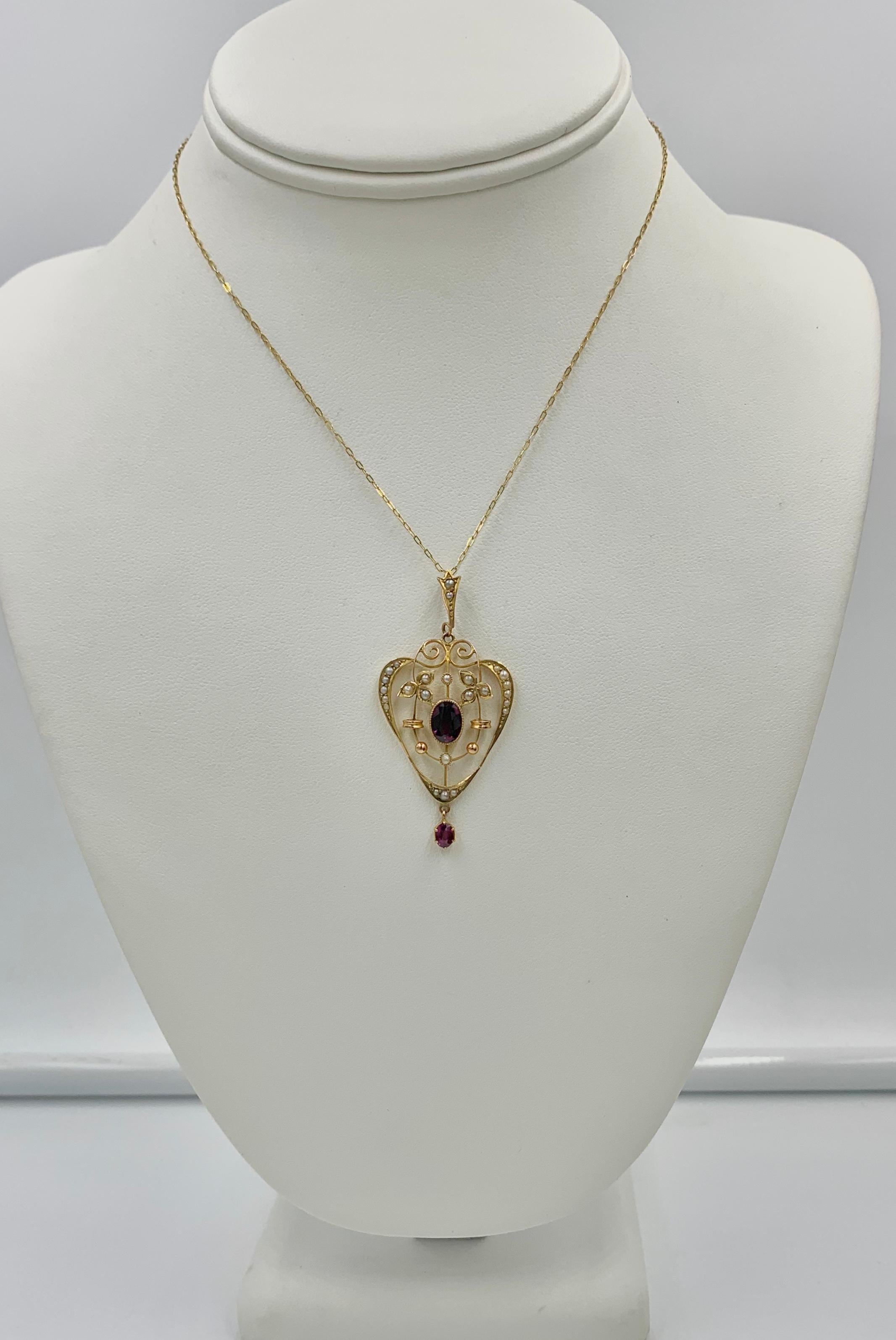 An Antique Victorian Heart Pendant set with two gorgeous Bohemian Garnets and lovely Seed Pearls in a heart shape pendant in an open work knife edge design.  In the center is a sparkling oval faceted Bohemian Garnet of great beauty.  At the bottom