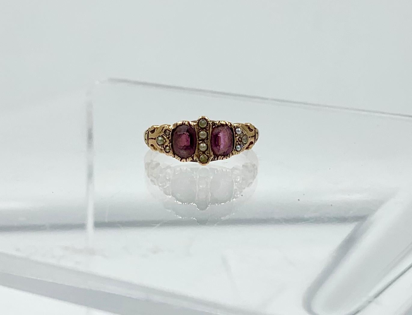 This is an Antique Victorian - Edwardian Ring with two gorgeous natural oval faceted Bohemian Garnets of stunning beauty. The Garnet gems are accented by Seed Pearls.   The jewels are set in a gorgeous engraved scroll motif setting in 10 Karat Rose