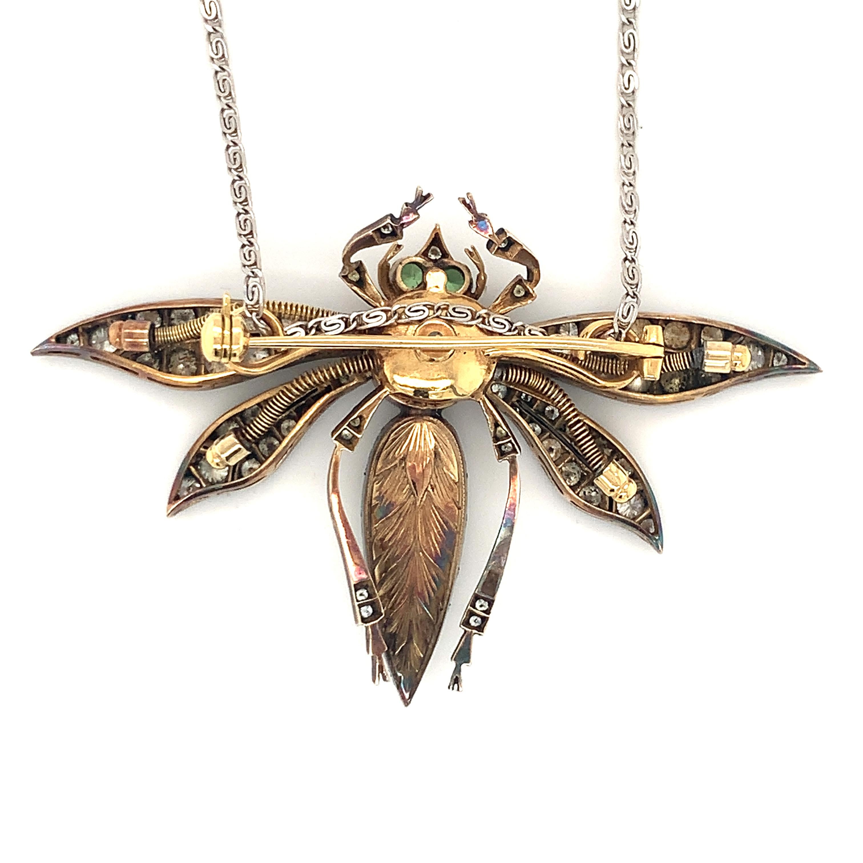 One gem-set dragonfly motif platinum and 18K yellow gold pendant / brooch featuring one bezel set, square cushion cut pink sapphire weighing 2 ct. and two bezel set, round brilliant cut green garnet eyes totaling 0.20 ct. The piece is enhanced by 75