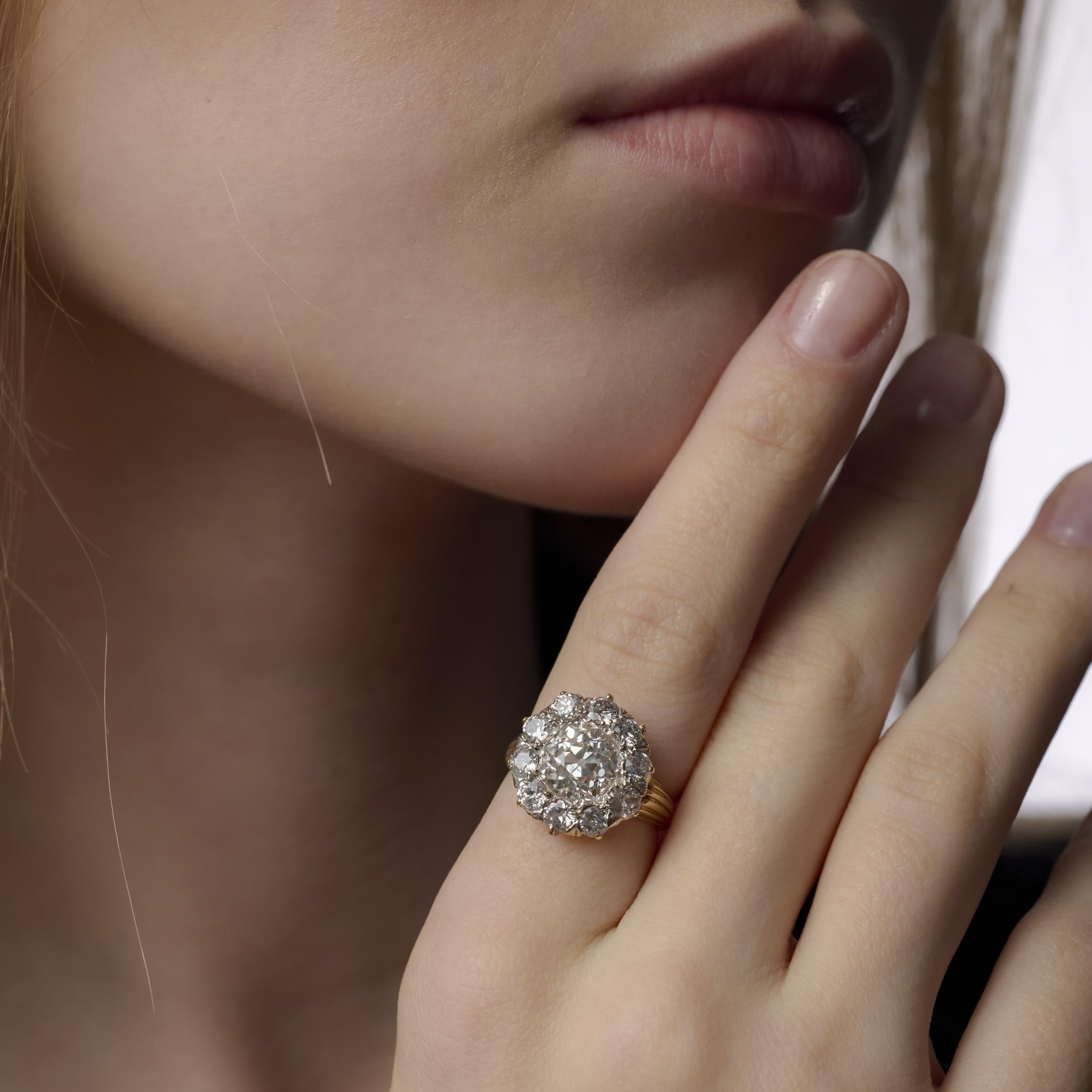 Este magnífico anillo victoriano exhibe un diamante de talla europea antigua de 3,02 quilates, certificado por el GIA, rodeado de diez brillantes diamantes de talla minera antigua, todo engastado en rico oro amarillo de 18 quilates para una opulenta