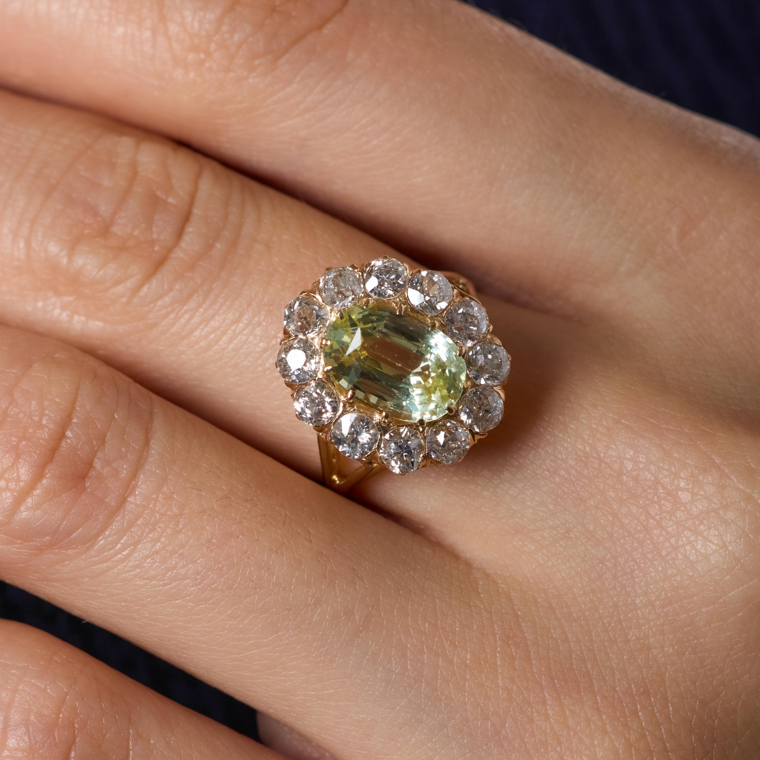 Cette ravissante bague victorienne à grappes rayonne d'un charme d'antan grâce à son remarquable saphir sans chaleur de 3,79 carats, affichant une rare et envoûtante teinte jaune-vert certifiée par le GIA. Son ton vif et changeant est à la fois