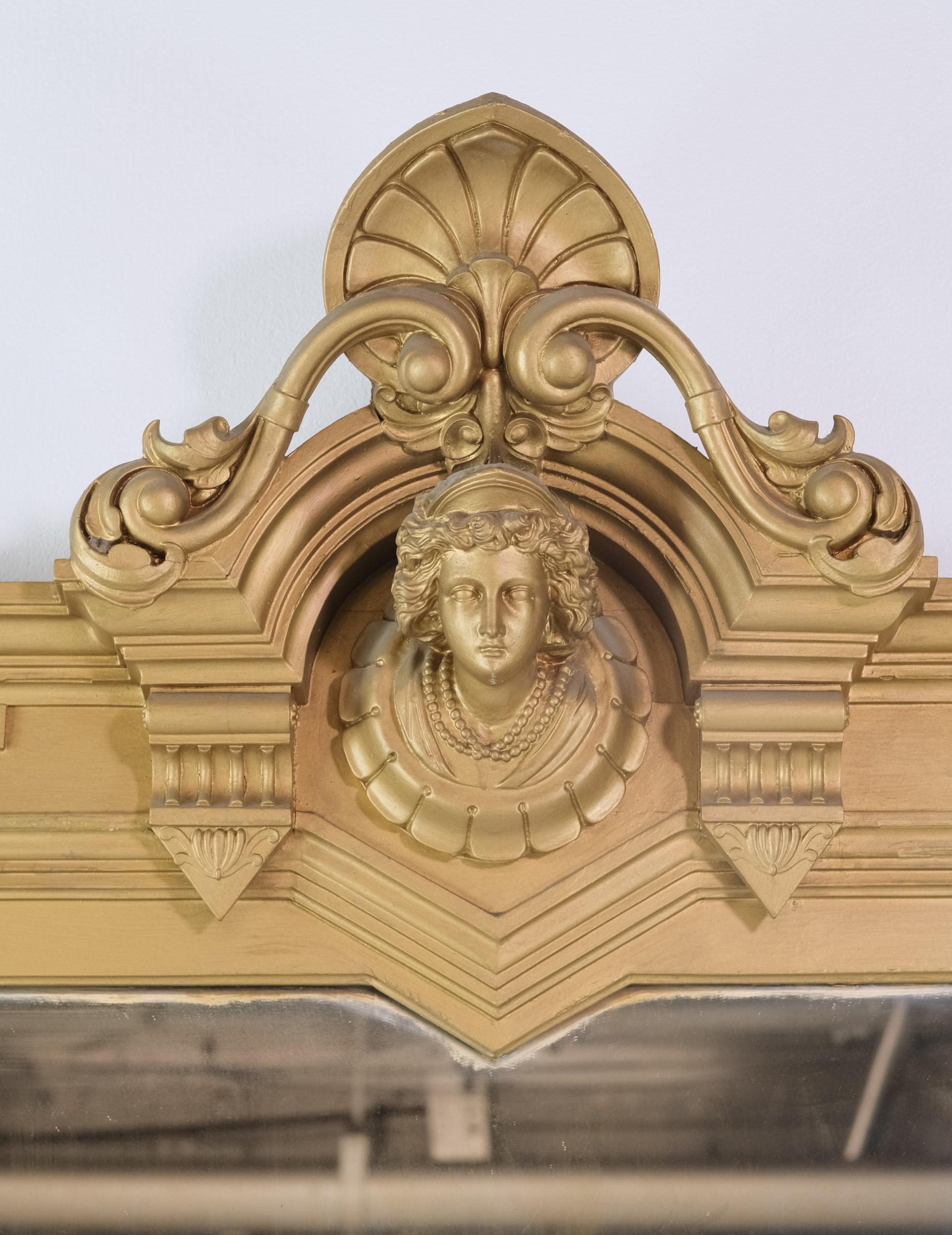Victorian gilded over mantel mirror with exquisite carved figural and floral details.  Some of the details are carved in gesso.  This stunning over mantel with intricate details has a very grand size. Please note, this item is located in our