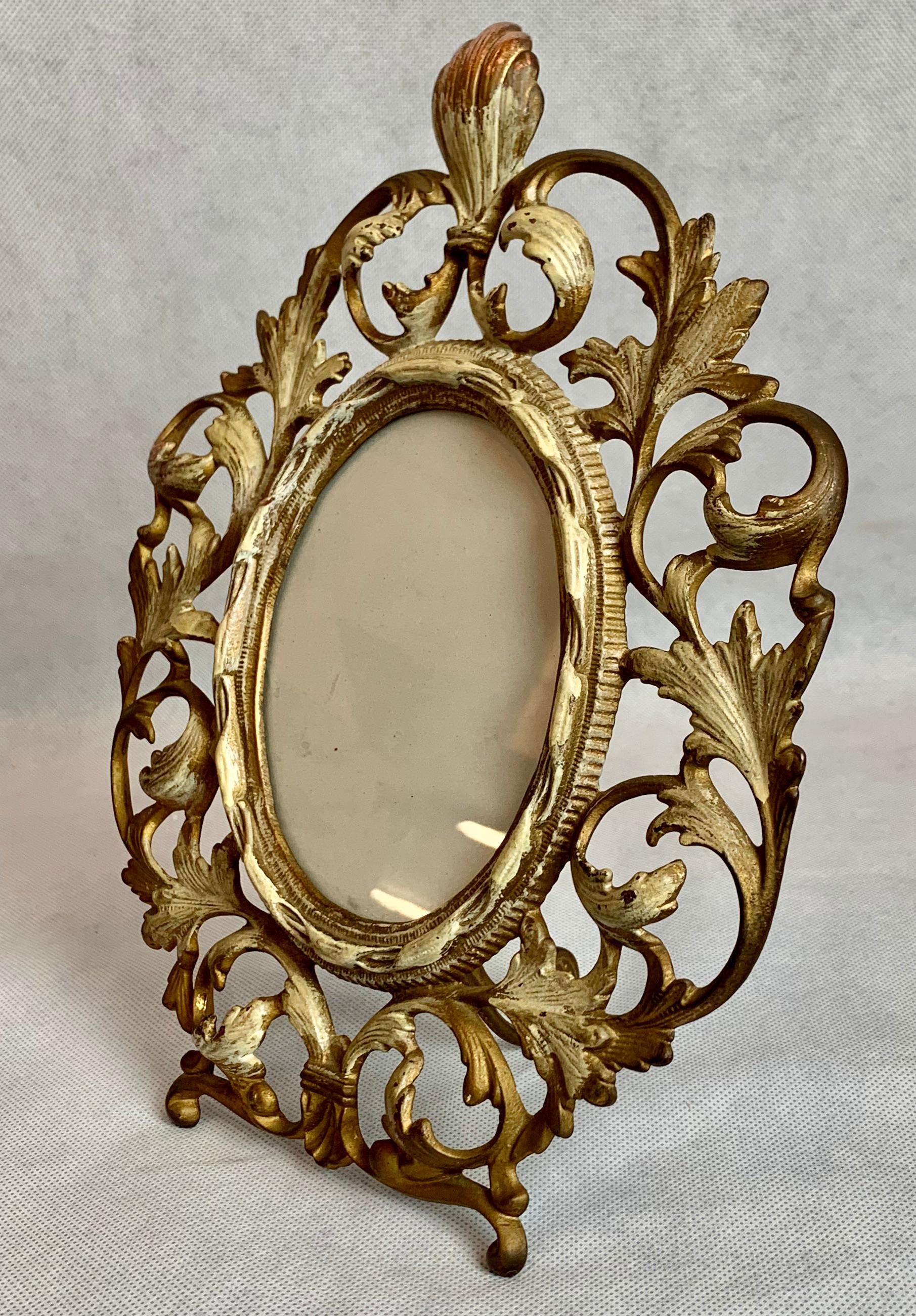 Victorian ovoid gilt and patinated photo frame with an easel back. The design is of scrolling acanthus leaves while the inner oval has a border of twisted ribbon.

Measures: H 11.25