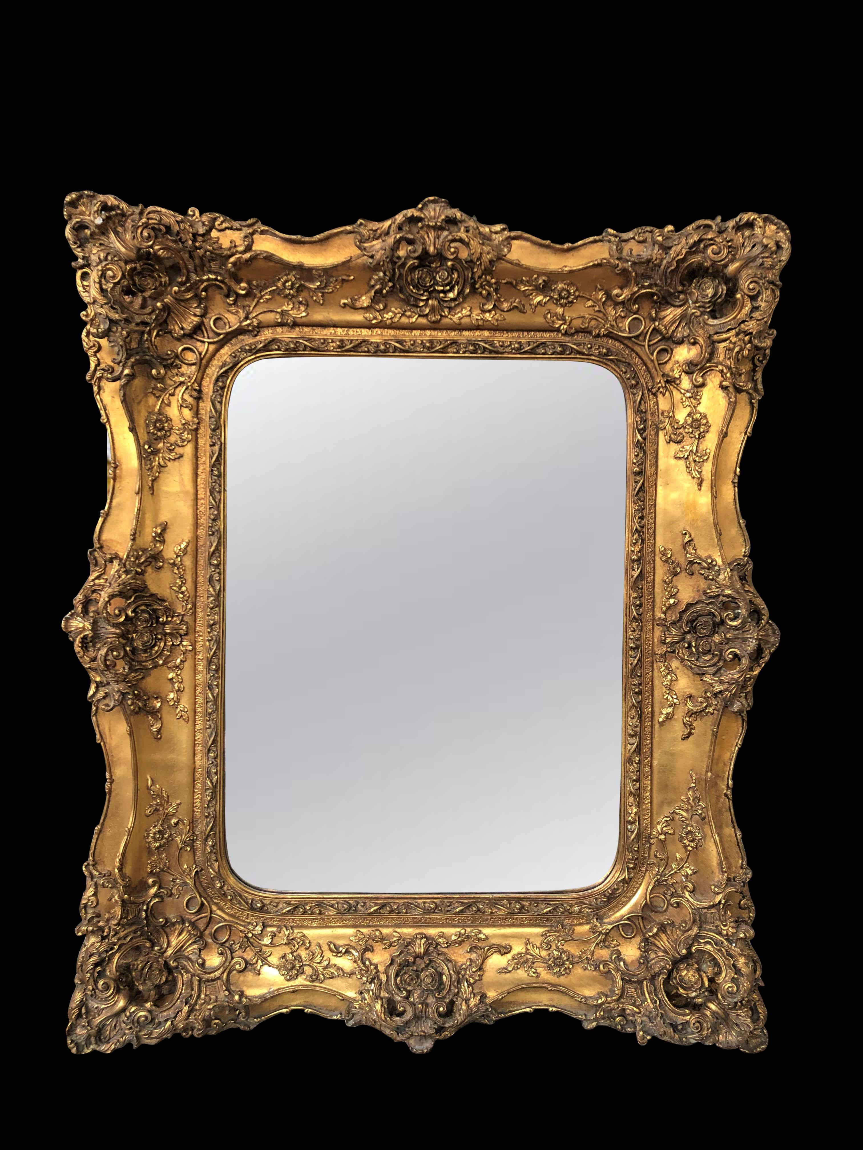 A stunning Victorian style gilt mirror with intricate frame and floral carving, 20th century. Can be hung portrait or landscape. Frame really makes this stand out, very florid details. Glass is clear and blemish free ready to add space and light to