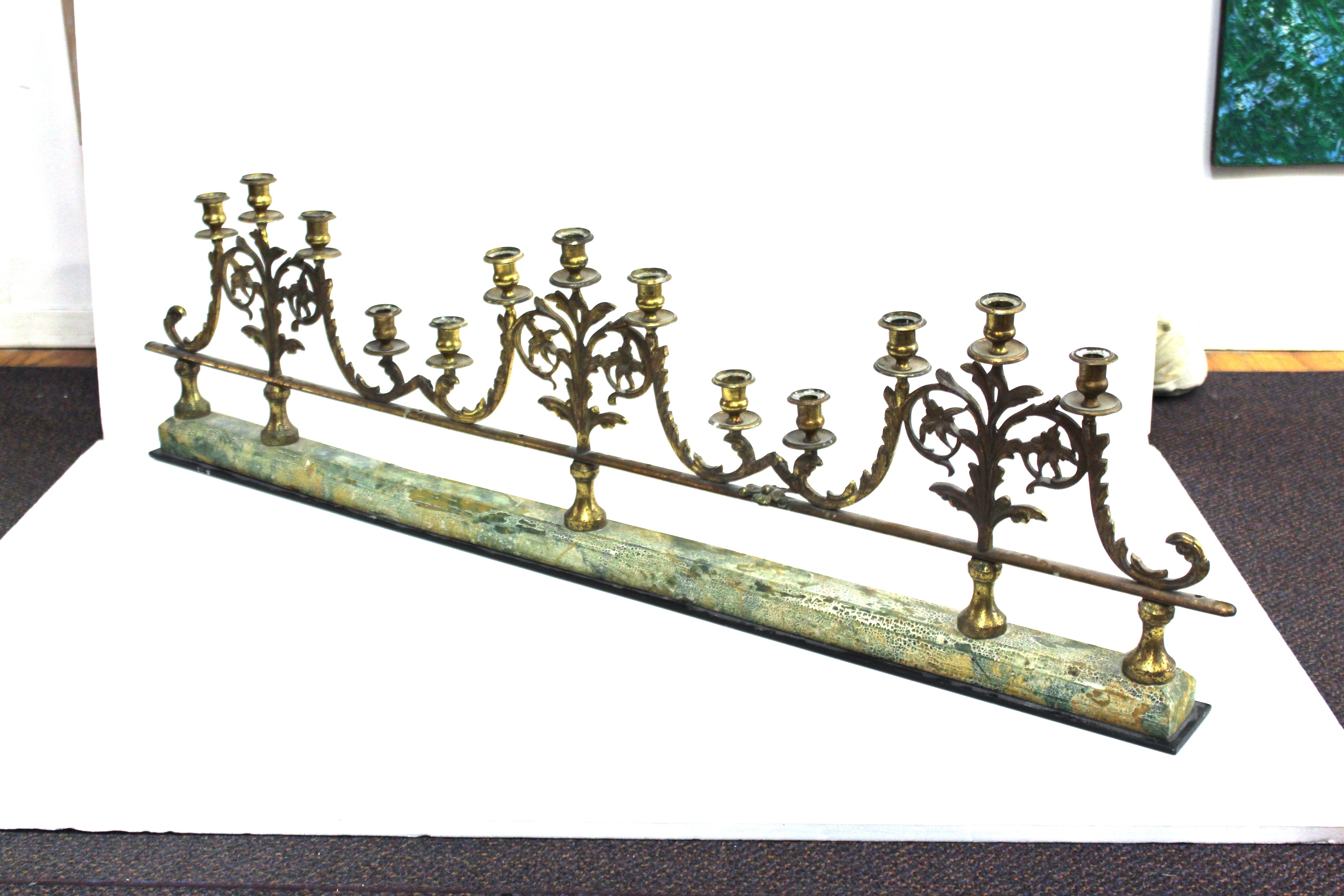 Victorian candelabra railing featuring three gilt metal candelabras with a total of fourteen candleholders. The candelabras are joined together at the extremities and mounted on a long painted wooden base. In great vintage condition with