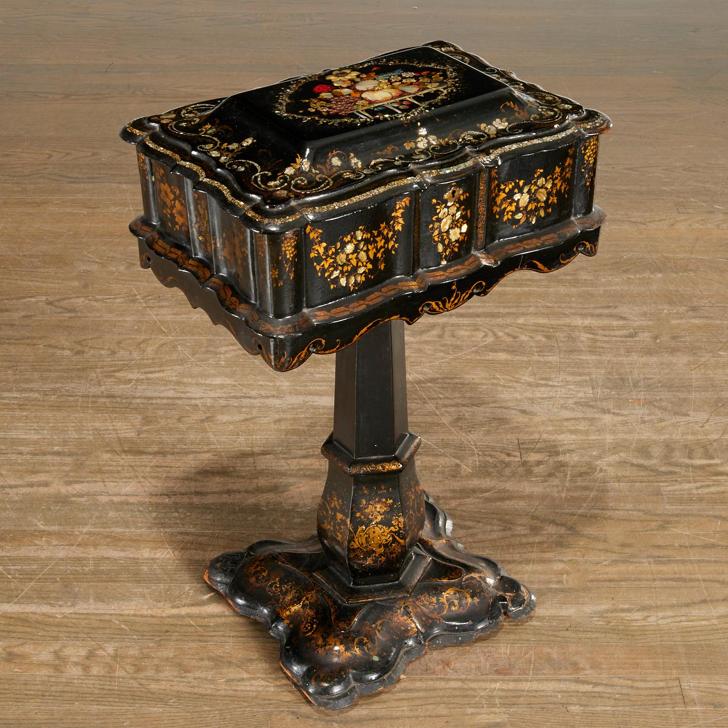 Beautifully decorated mid-late 19th c, England, black lacquered papier-mâché sewing stand. Decorated with gilt, mother-of-pearl and polychrome paint, opening to cloth-lined interior. Christie's auction tag and label to underside. Lavishly decorated