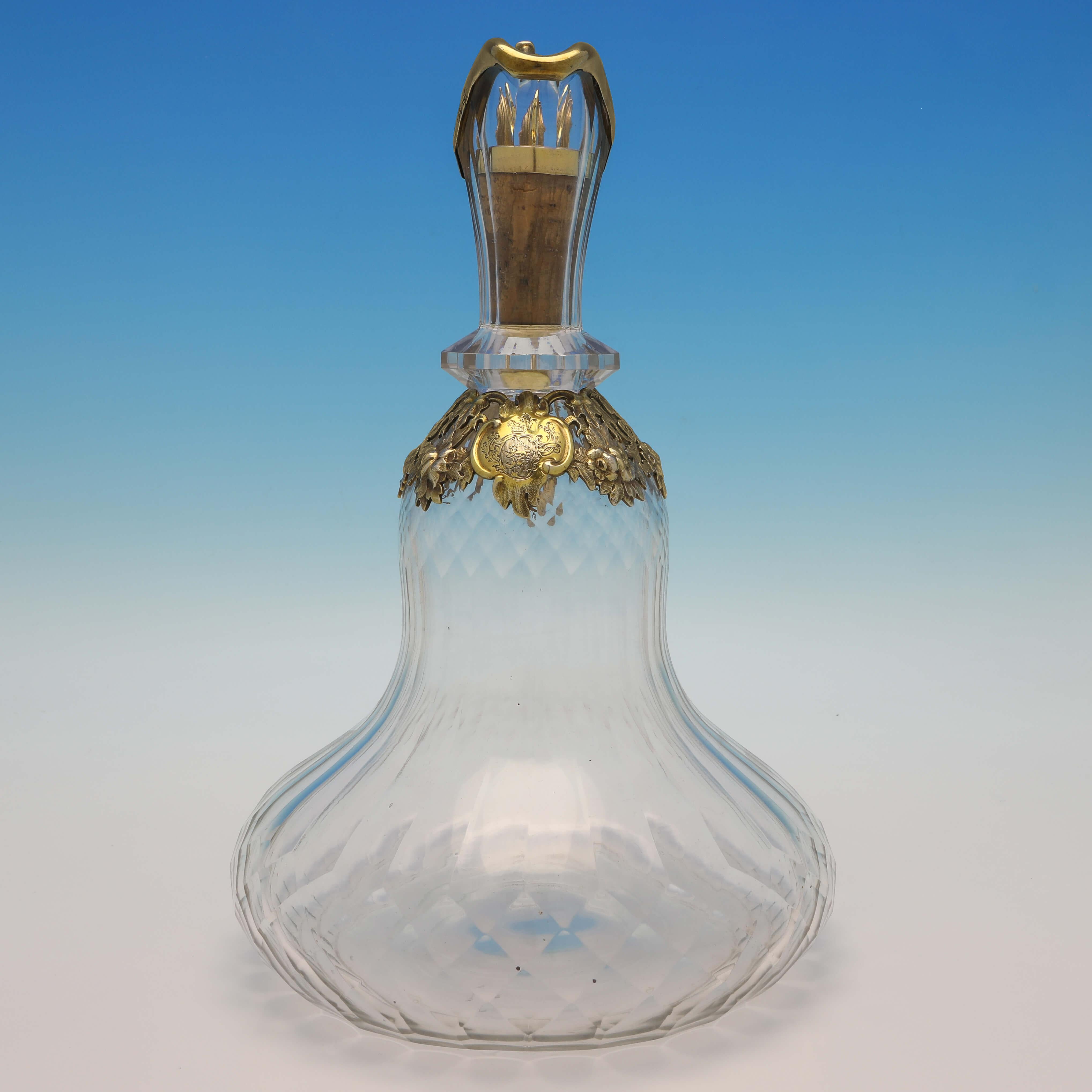 Hallmarked in London in 1854 by Charles & George Fox, this striking, Antique Sterling Silver Claret Jug, features a wide glass body which would add stability, a gilt mount and handle, a cork stopper with gilt silver ring, and an engraved crest and