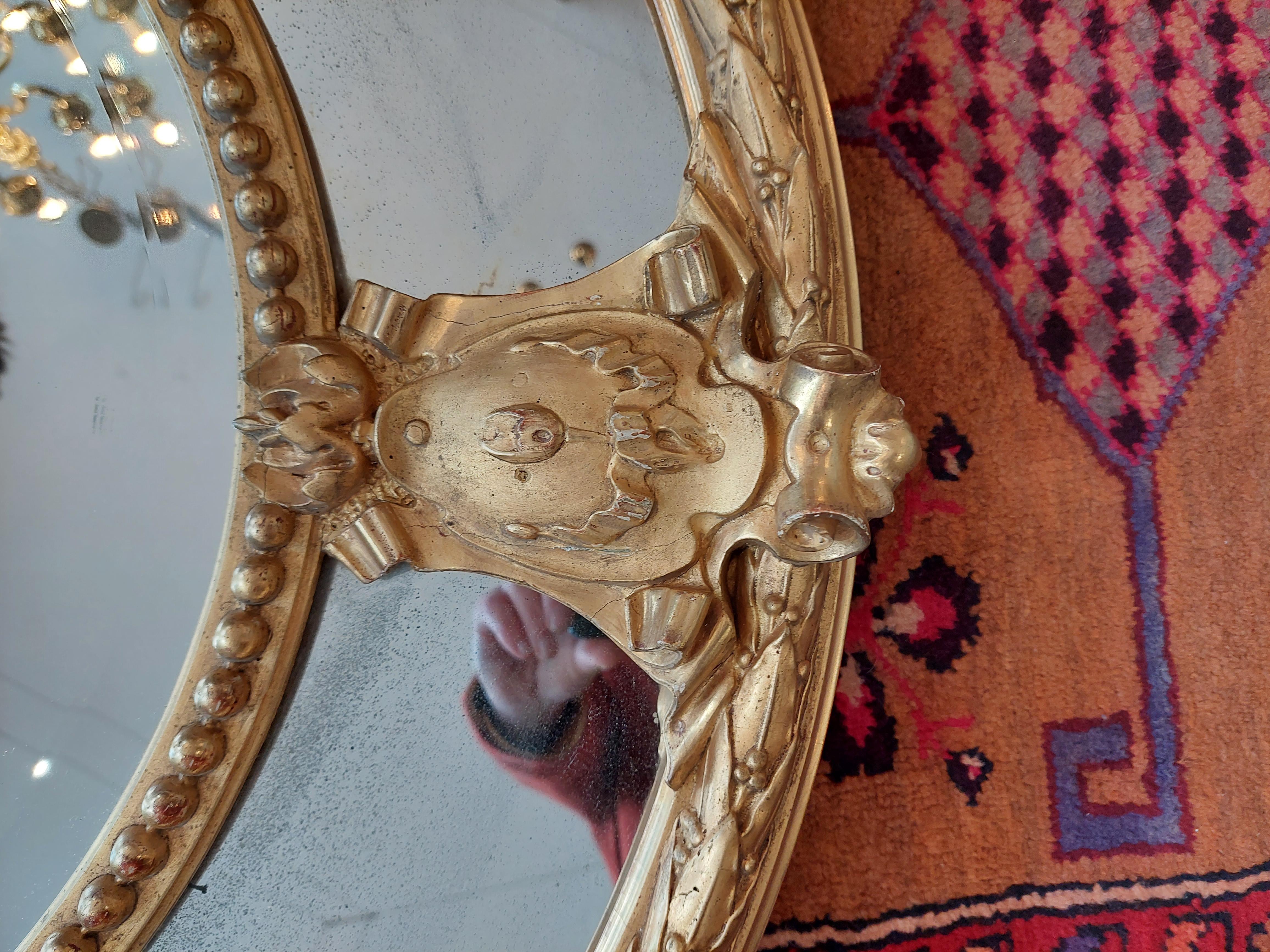 19th century giltwood and gesso oval wall mirror, surmounted with a pair of birds, quiver of arrowsand a torch all entwined within oak branches and leaves, over the central bevelled mirror plate, enclosed by a beaded frame united to the outer frame