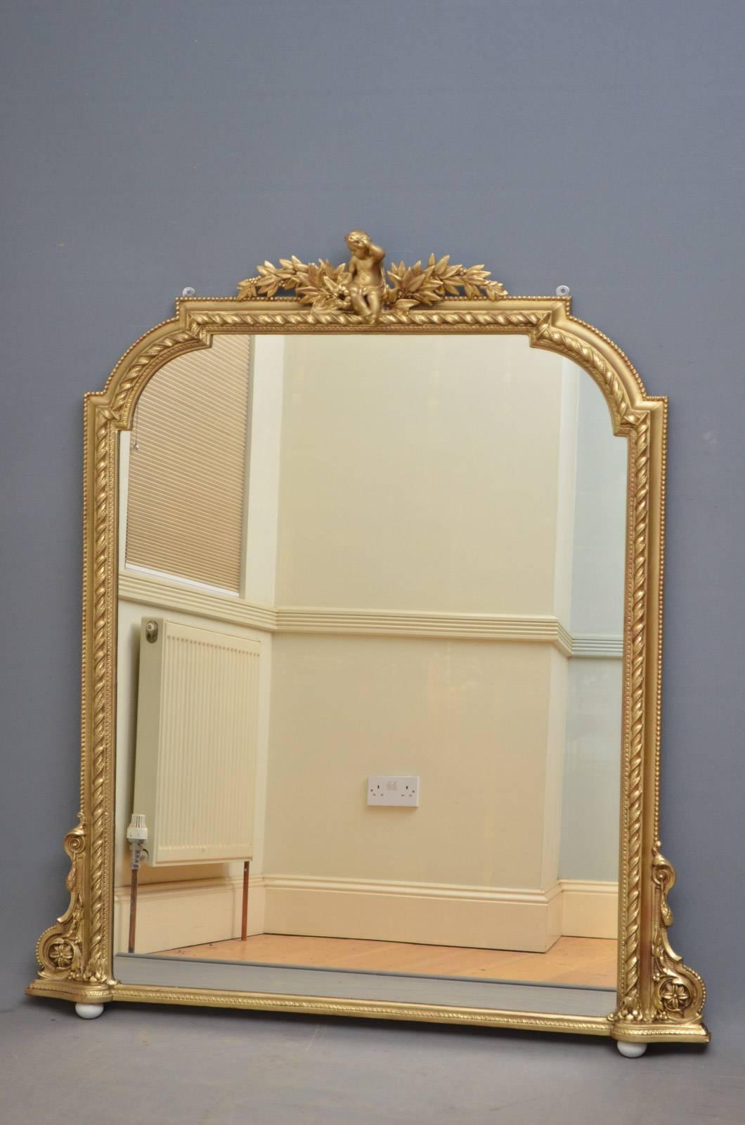 Sn4311, Victorian gilded overmantel mirror, having original mirror plate with some foxing and finely carved frame with cherub to centre and fine scrolls to base, standing on removable porcelain feet. This antique wall mirror has been refinished and