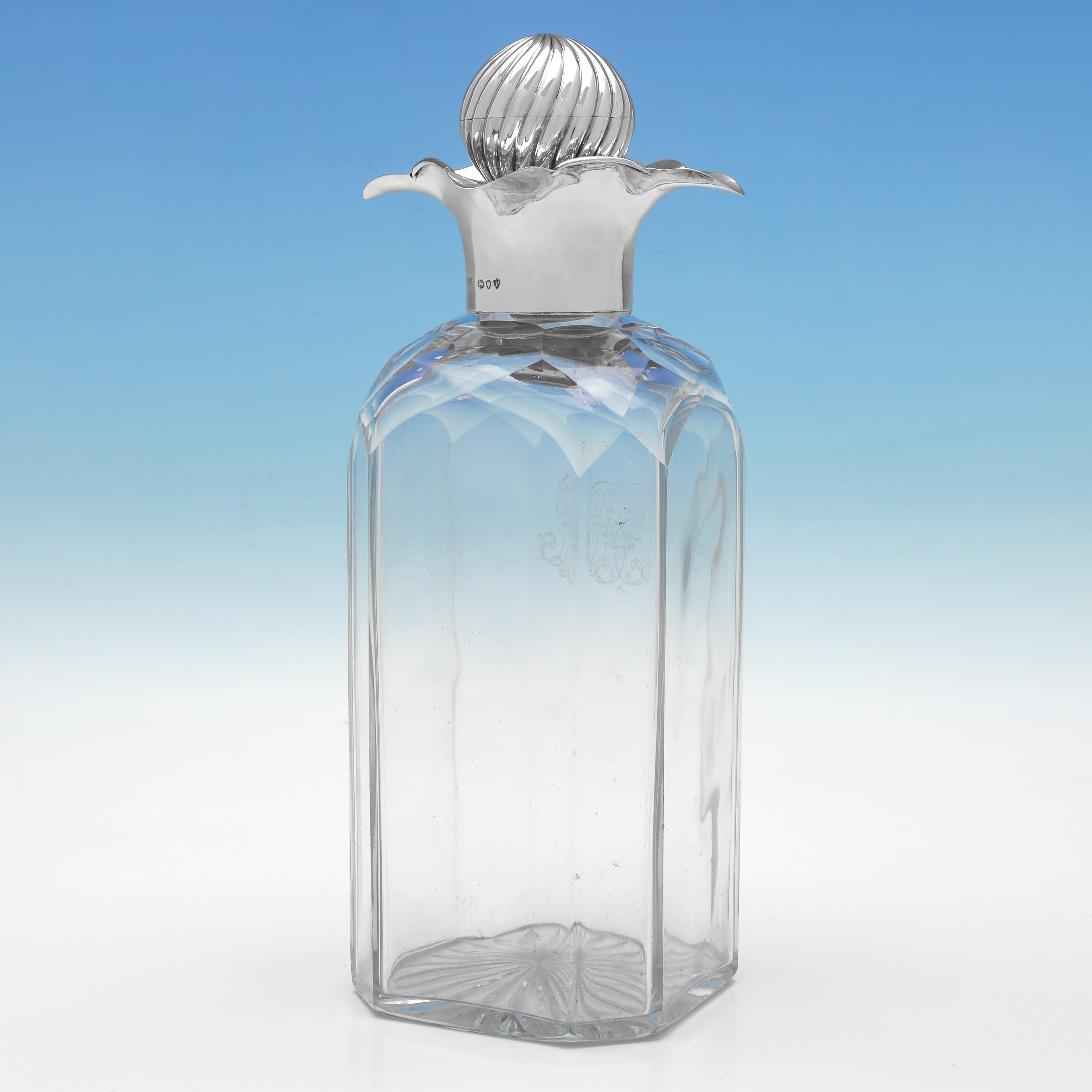 Marcada en Londres en 1890 por Joseph Braham, esta antigua jarra victoriana de plata de ley y cristal es de forma cuadrada y tiene una montura lisa de plata con 4 labios y un tapón estriado de cristal y plata. El cuerpo de cristal está grabado con