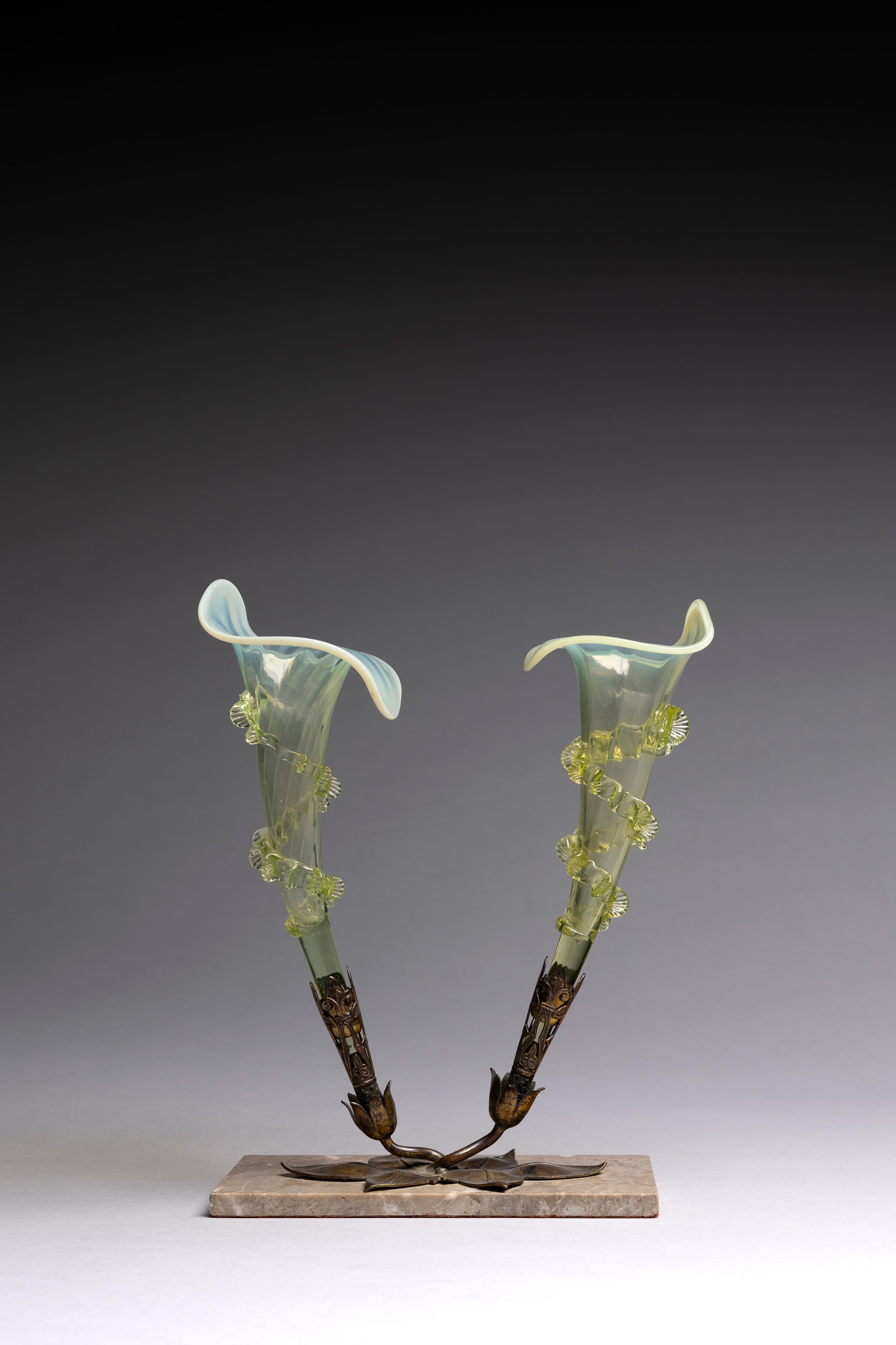 Jarrón victoriano de cristal, posiblemente de John Walsh Walsh, fabricado a finales del siglo XIX.

Esta hermosa pieza es muy escultural, modelada como dos calas gemelas en vidrio de vaselina verde antiguo, montadas en un adorno de latón sobre una