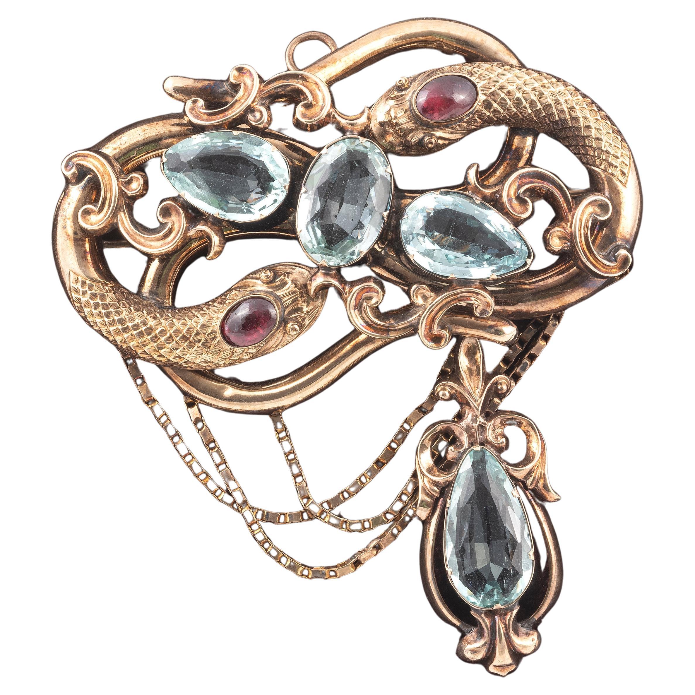 A 19th century aquamarine and garnet snake brooch/pendant, 
fine and elaborate chased gold finish to the body with chain,set with oval-shaped aquamarines and cabochon garnets, with red stone eyes in gold, 7cm high
Weight: 21.16gr.

