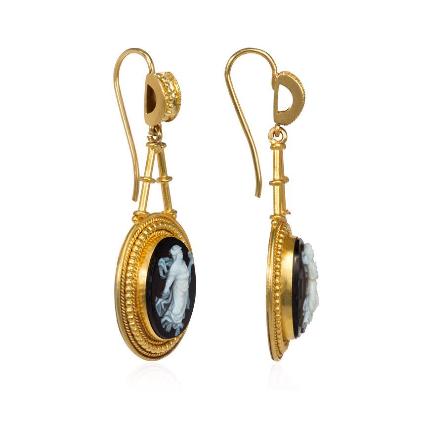 A pair of antique gold earrings in the Etruscan style comprised of sardonyx cameo pendants depicting robed women in bead and wirework decorated oval surrounds with corresponding surmounts, in 18k. 
