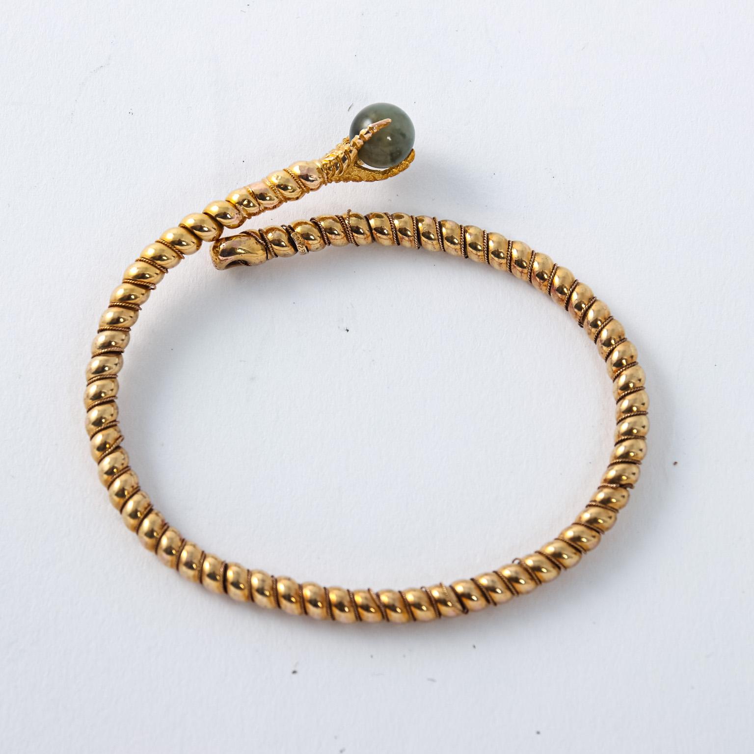 Circa 19th century Victorian 20 Karat Gold bangle bracelet in a rope design with claw on the end holding a 6.00 Millimeter Cat's Eye Tourmaline held firmly by the prongs of the claw. On the end of the top piece features a hallmark. Weight 10.5