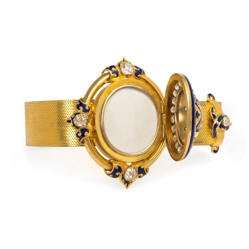 An antique woven gold jarretière bracelet of adjustable size, centering on an oval starburst diamond bulla in a diamond surround and with blue enamel decoration, in 18k; centerpiece opens to reveal a locket compartment.