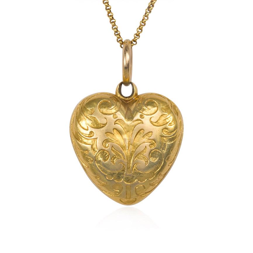 An antique gold puffed heart locket pendant with black enamel decoration on one side and chased decoration on the verso, in 15k, suspending from a 15k gold chain.  England

Dimensions: heart is approximately 1 1/4