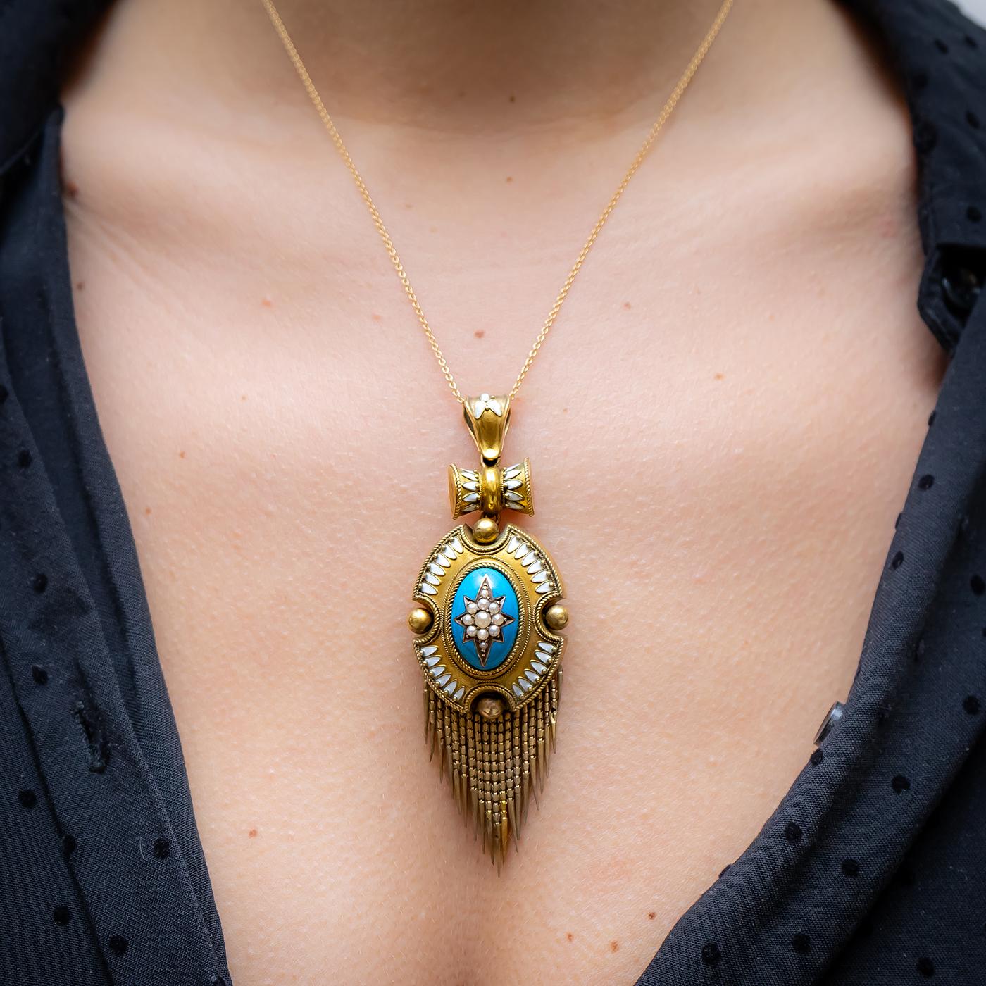 A Victorian seed pearl and enamel fringe pendant, with a central oval blue enamelled cabochon, inlaid with a seed pearl set star, in an oval decorative surround, with rope and beading to the edges and white enamel detail throughout, larger gold