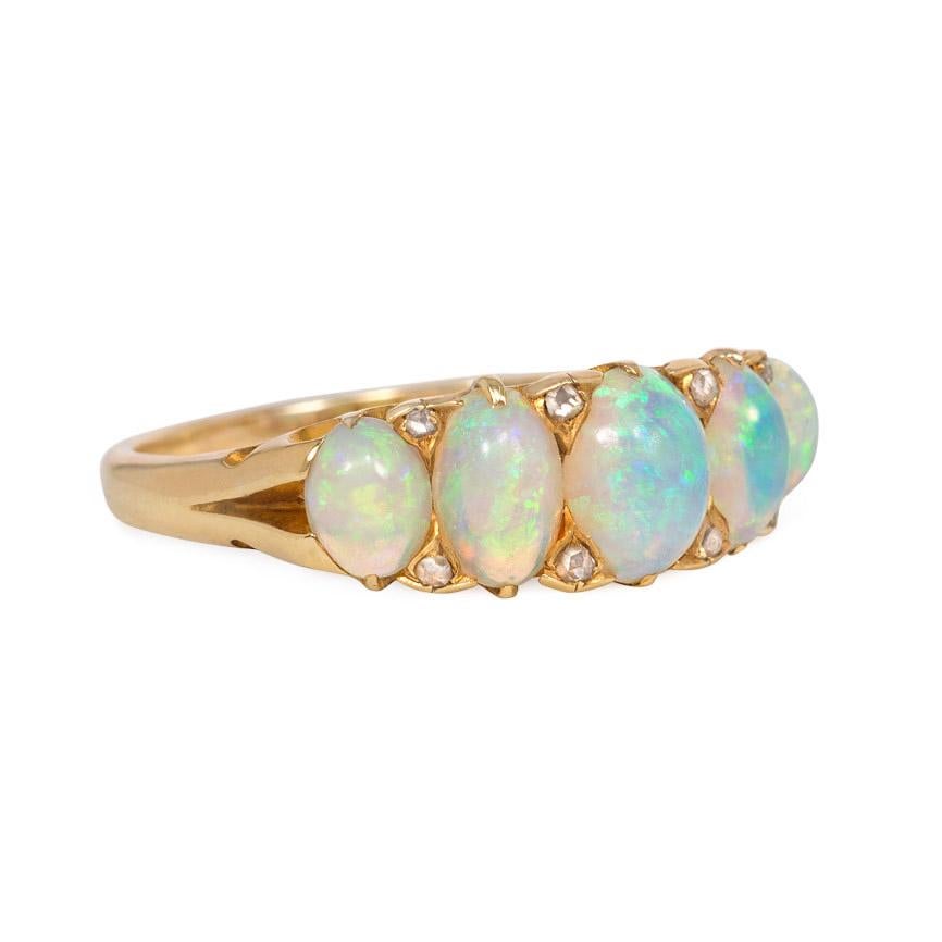 An antique Victorian gold and opal half hoop ring comprising five opals with rose-cut diamond embellishment, in 18k mount with festooned gallery.  Approximately 6.5mm at widest

Current ring size: US 7; please contact us with re-sizing inquiries