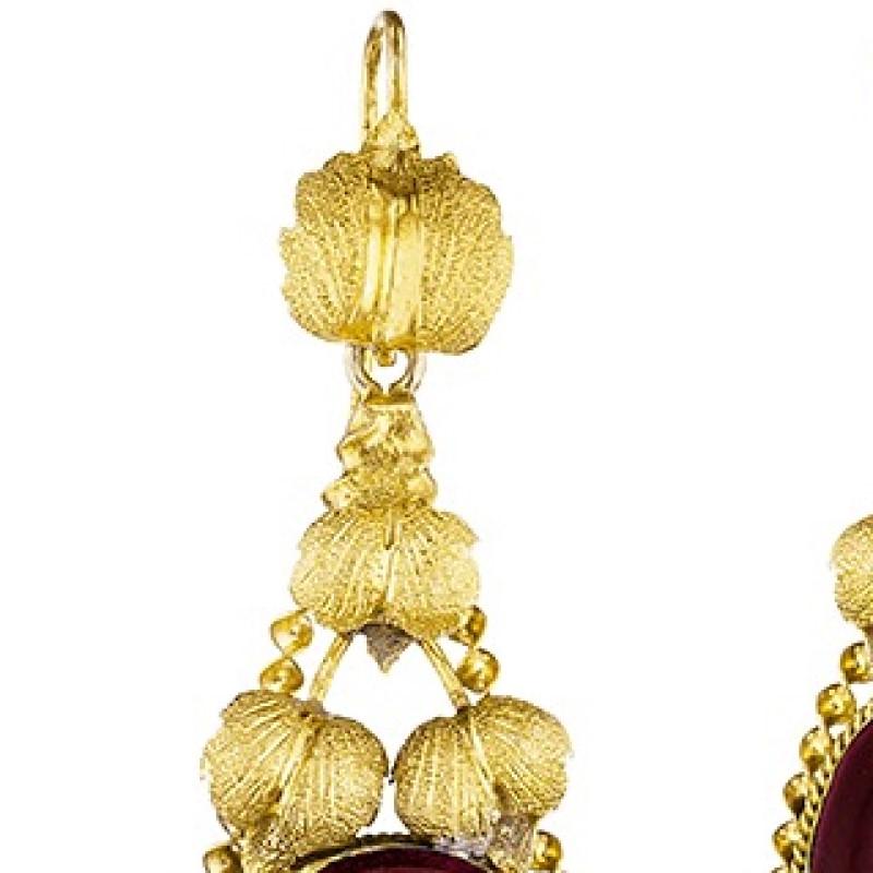 A pair of English Victorian 15 karat gold earrings with garnet. The earrings have large oval cabachon almandite garnets framed by intricately twisted gold 