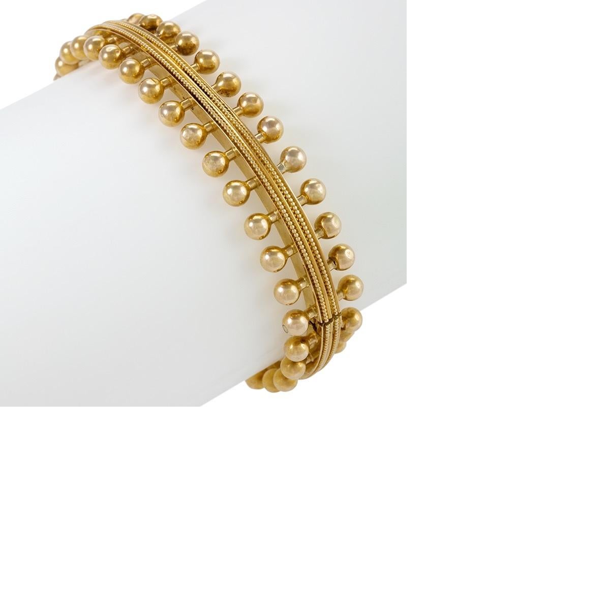 An English Victorian 18 karat gold bracelet by famed Renaissance Revival jewelry designer Robert Phillips. The bangle features a central band of delicate granulation work, with Phillips's hallmark round motifs decorating either side. Phillips was a