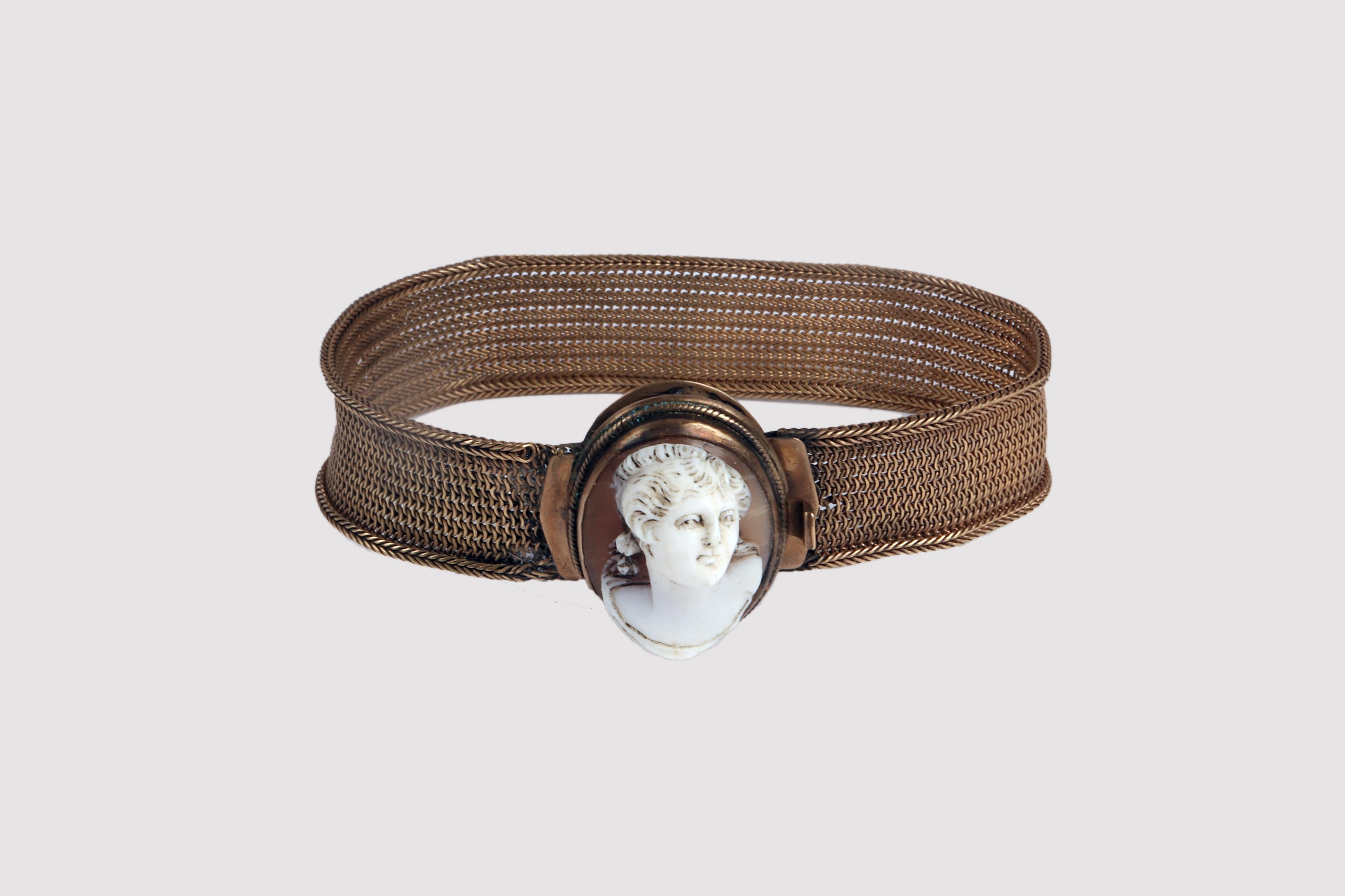 Victorian era bracelet with shell cameo. The bracelet is made with a band of woven 12K gold wire. The edges are reinforced with a continuous herringbone pattern. The clasp consists of a gold oval corded in filigree which sets a cameo depicting a