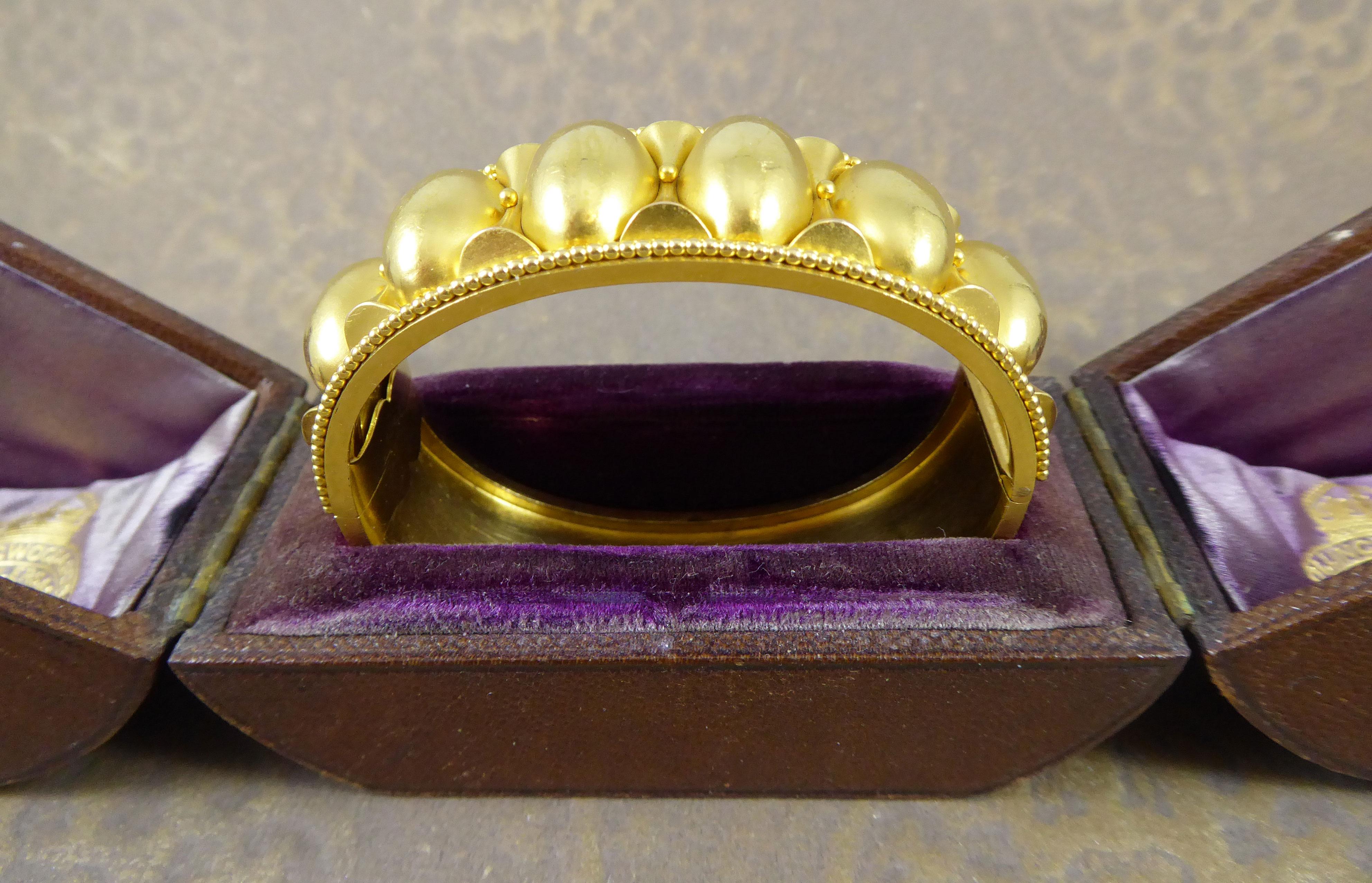 From the Victorian era and circa 1880s a half hinged cuff bangle with hollow oval domed decoration to the front half bordered on either edge with  a granulation bead border.  Plain polished back, marked inside  