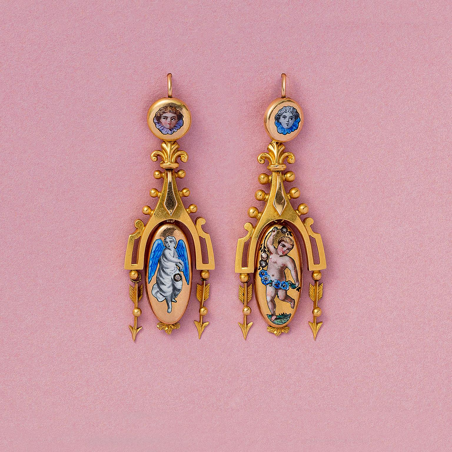 A pair of gold dangling earrings, one with an enameled dancing putto and one with an angel, set with small old-cut diamonds and decorated with little dots and arrows and fleur de lys, with locket compartments at the back. Marked: CG (possibly