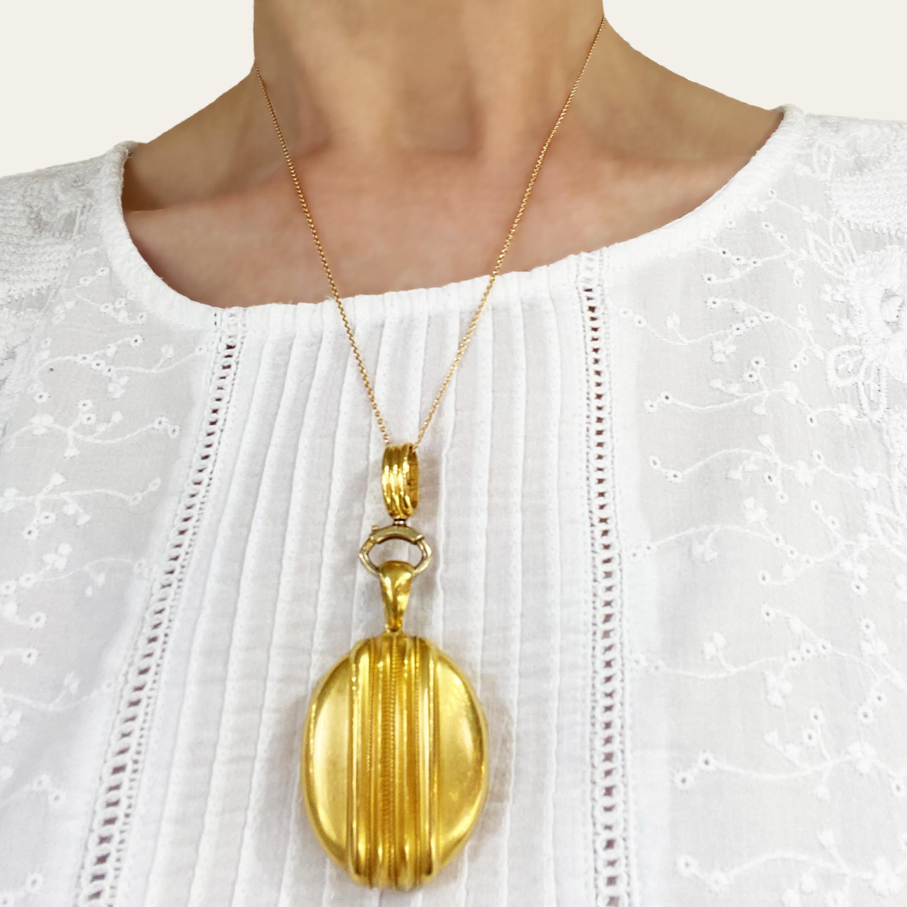 A Victorian gold locket, with an oval outline, with ridge and wire twist Etruscan style work on both sides, with a plain gold bail and a detachable ridged hanging loop, on a large bolt ring. The locket opens to reveal two picture lockets, with cream