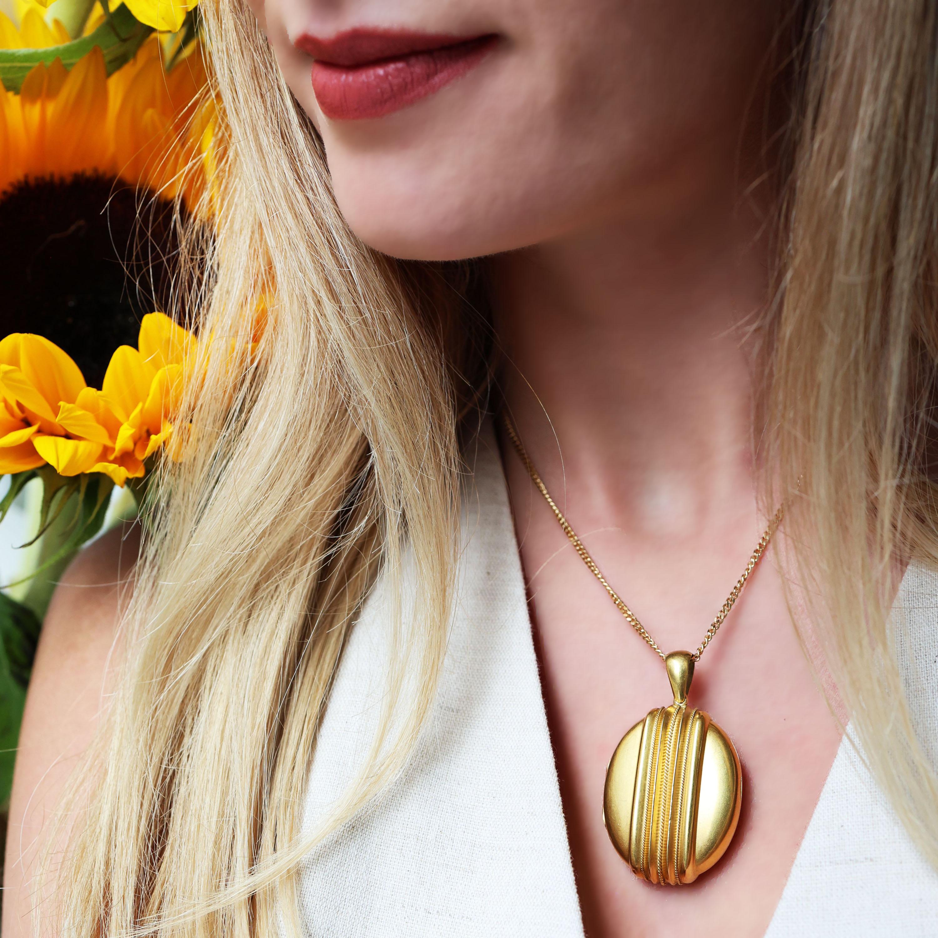 A Victorian gold locket, with an oval outline, with ridge and wire twist Etruscan style work on both sides, with a plain gold bail and a detachable ridged hanging loop, on a large bolt ring. The locket opens to reveal two glass covered picture