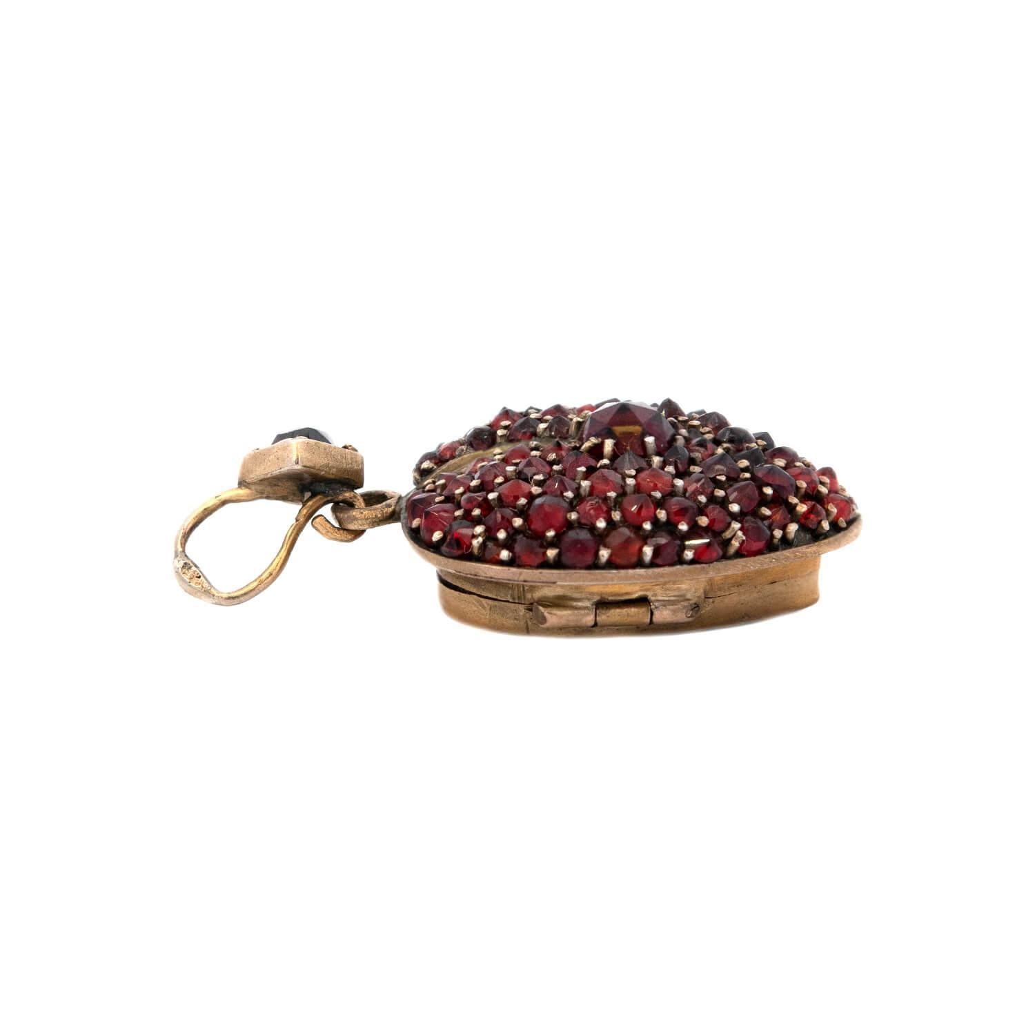 A gorgeous locket from the Victorian (ca1880s) era! Gold filled, the entire front surface of this petite locket is encrusted with bead-set garnet stones. The center of the locket features a slightly larger garnet, and all of the stones are