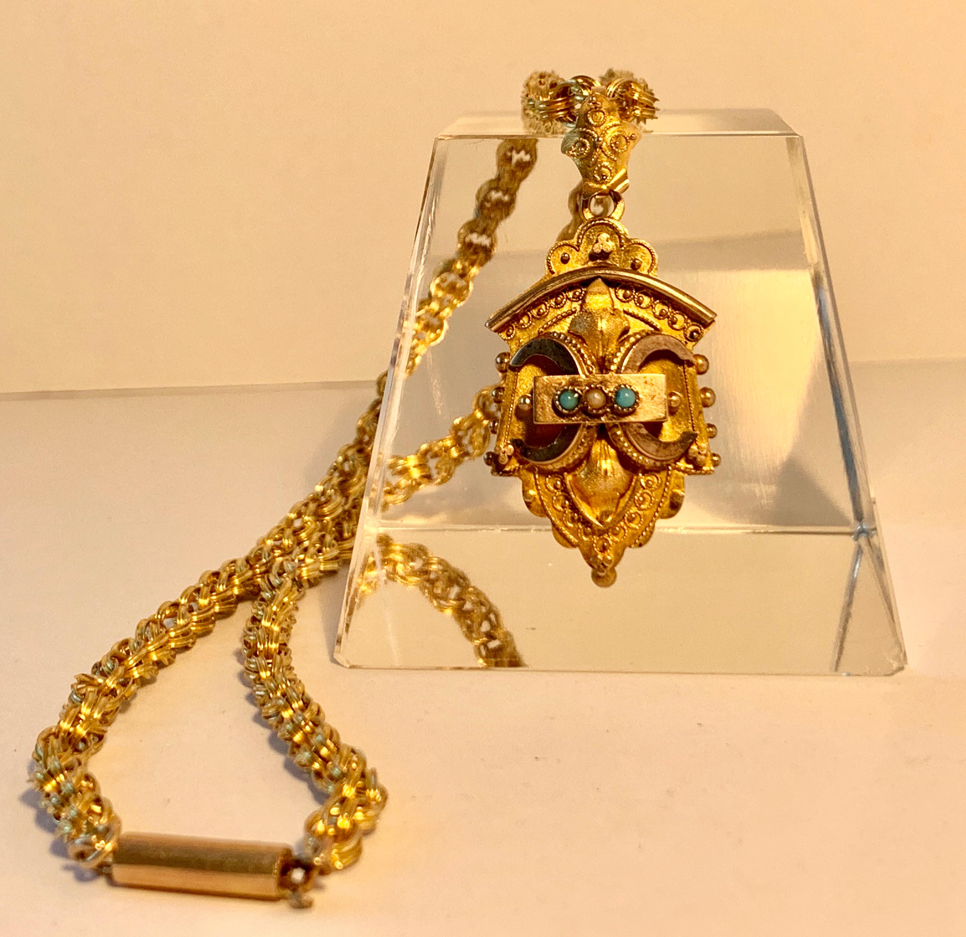 Goldgefüllte viktorianische Medaillon-Halskette mit zwei kleinen Türkissteinen und einer Saatperle.  Das ovale Medaillon ist mit einem schildförmigen Bügel an der Kette befestigt.  Das Medaillon selbst lässt sich auf der Rückseite öffnen.  Die Kette