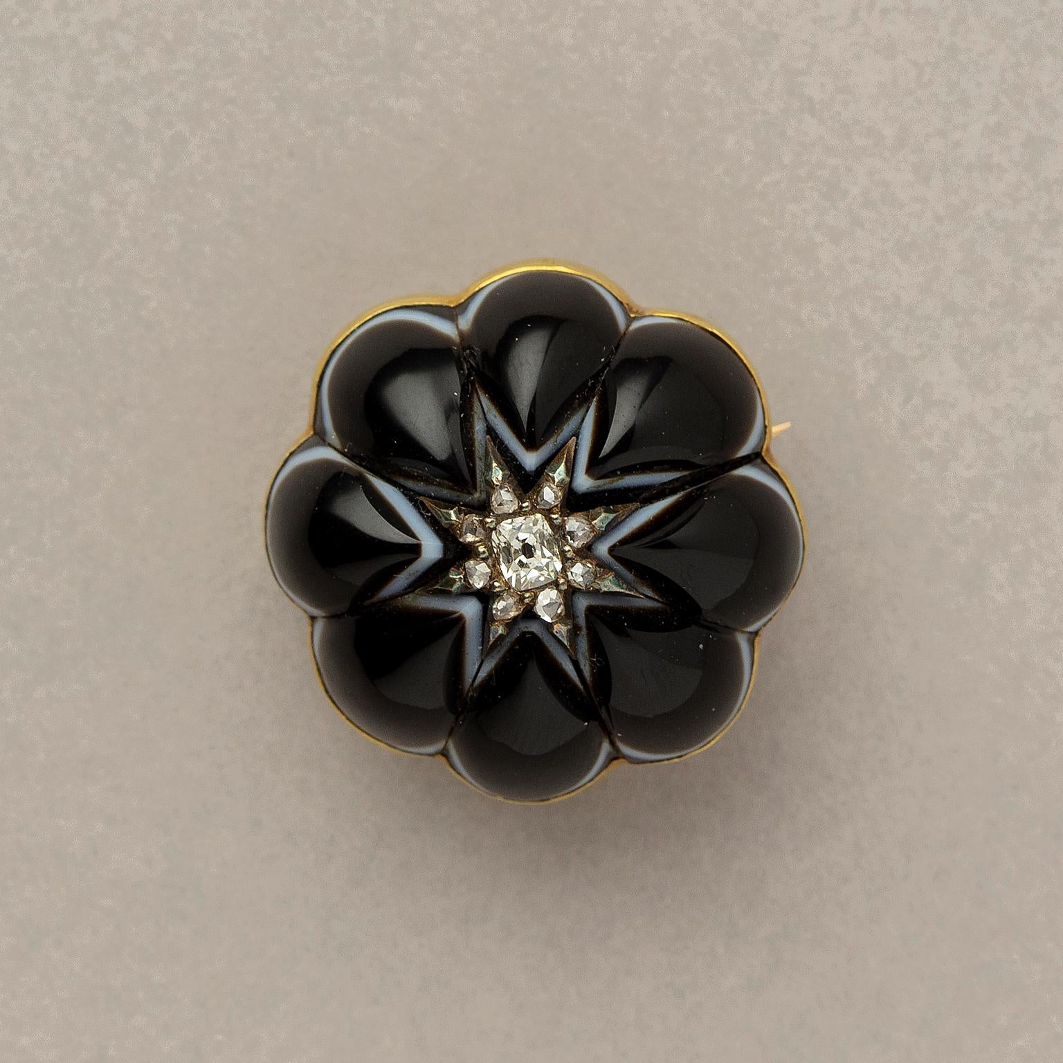 An 18 carat gold flower brooch with pear shaped onyx leaves, in the middle a cushion cut diamond surrounded by old cut diamonds (app. 0.23 carat in total), English, circa 1890.

weight: 14.29 grams
size: 2.7 x 2.7 cm