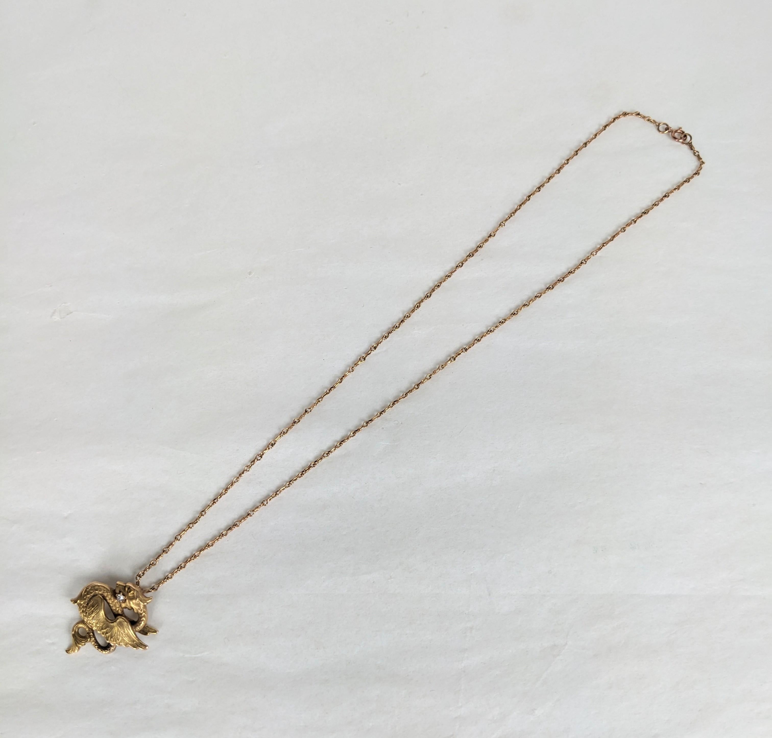 Grazioso ciondolo vittoriano in oro a forma di grifone con accento di diamante sulla bocca. La catena è una maglia ornata di colore rosa in oro 10k abbinata a questa spilla a forma di grifone della fine del XIX secolo in oro 14k. 
L'ornato grifone