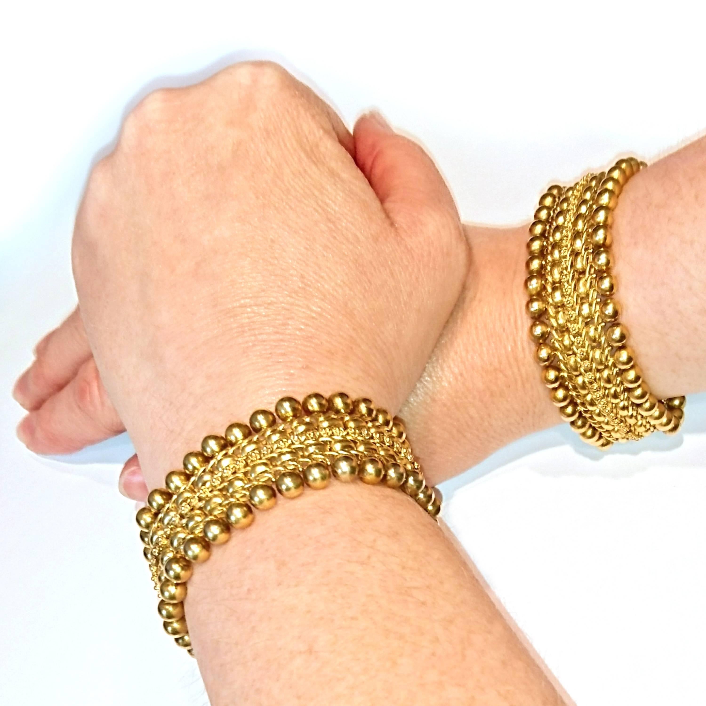 A pair of Victorian gold bracelets, with a woven design, featuring a row of flowers, superimposed on V shaped links, flanked by D cross-section links and diagonal links, with gold bead detail to each edge. The bracelets can be put together, to wear