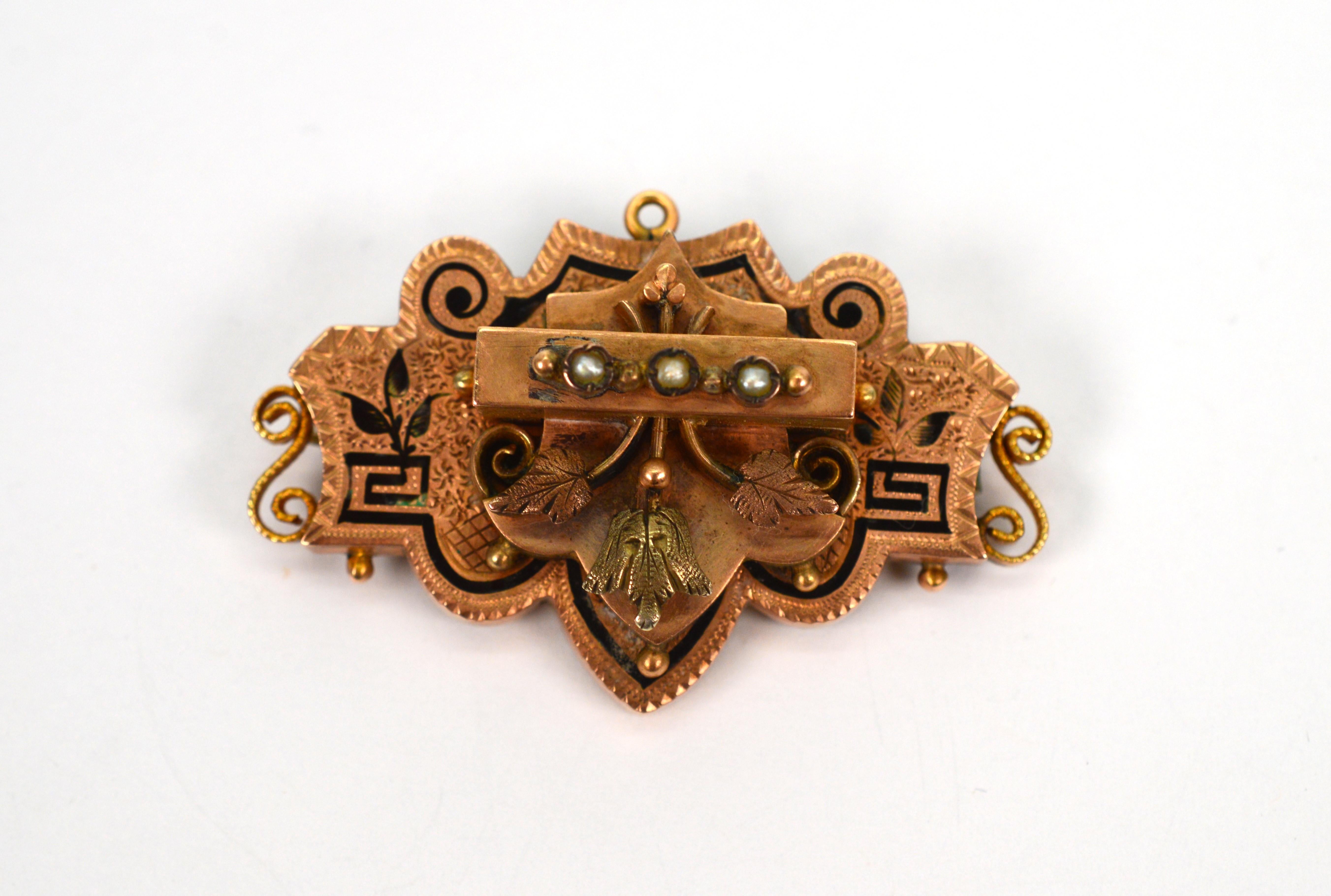 Ornate metalwork in 14 karat yellow-rose gold is graced by artistic characteristics attributed to the Victorian era and packed into this petite brooch from the period. Scroll shapes and defining lines with hand painted black enamel and pearl accents