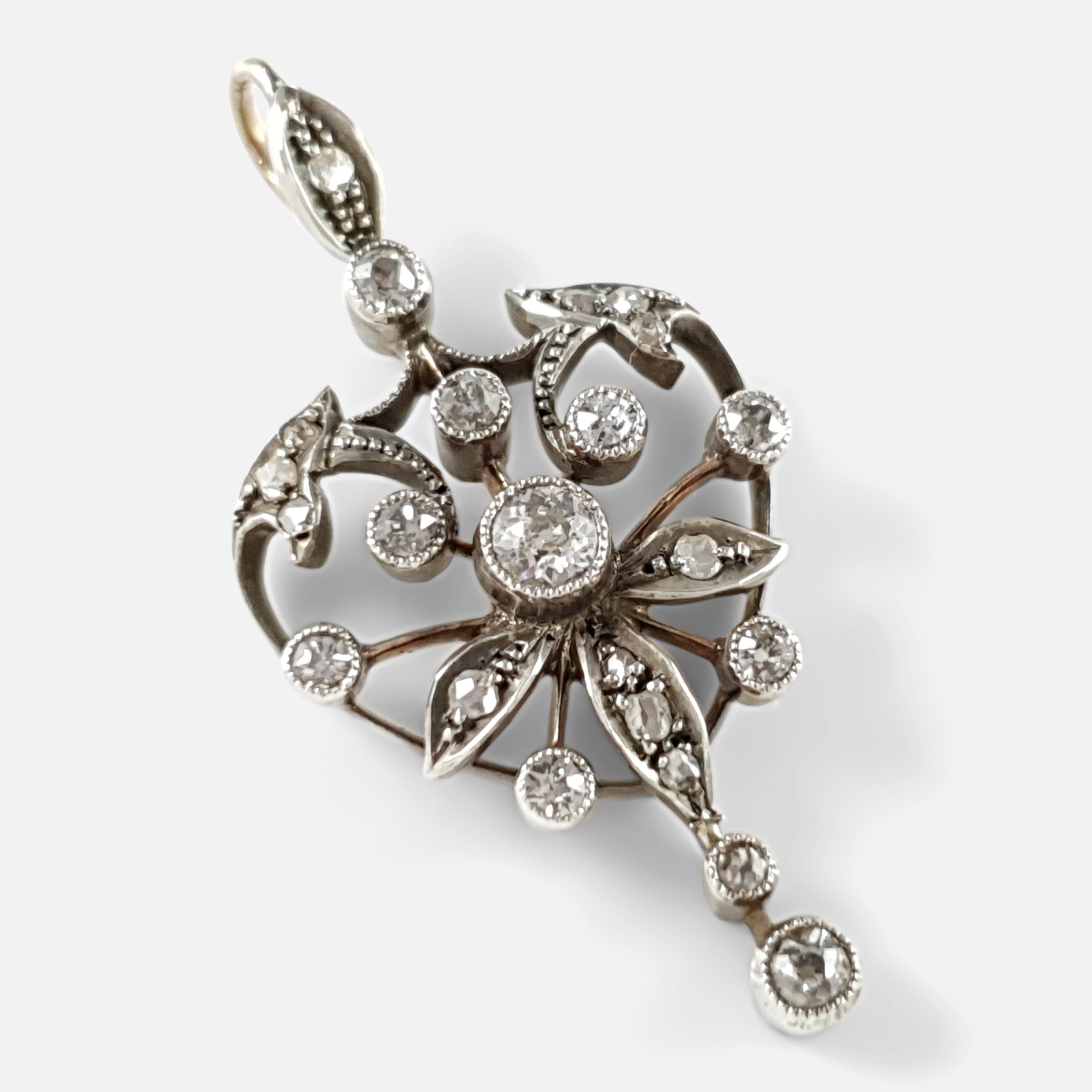 A late Victorian 0.57ct diamond pendant. The silver fronted and gold backed pendant is designed as an openwork heart-shaped foliate panel, with graduated old and lasque-cut diamonds in millegrain and grain settings, suspending a similarly set drop.
