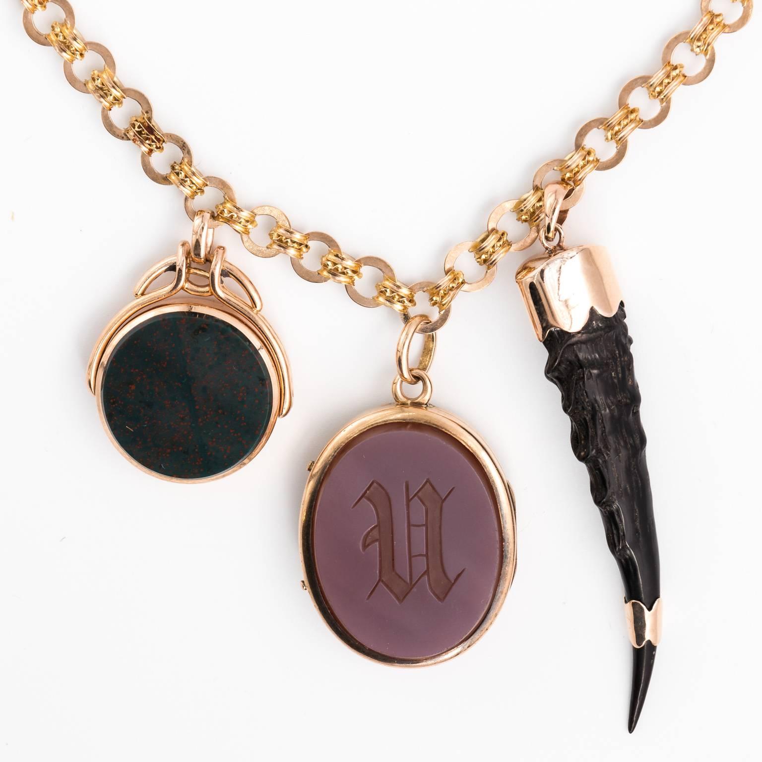 Circa late Victorian collage watch chain necklace that features bloodstone and carnelian fobs. a carnelian and bloodstone locket, and a horn in 14 karat gold. This piece is reversible and can be worn on either side.