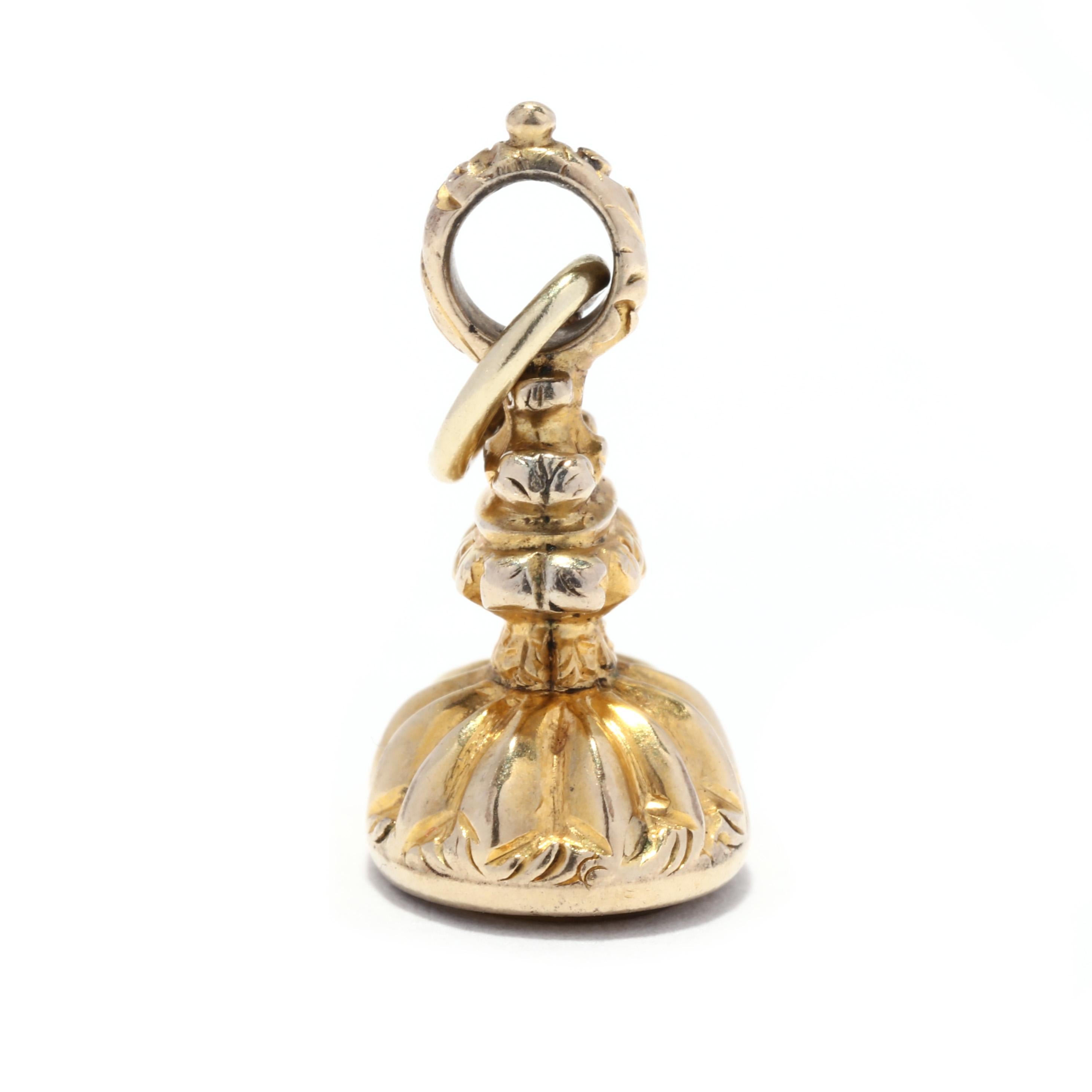 A Victorian 10 karat yellow gold citrine intaglio watch fob charm. This mini charm features an ornately engraved watch fob charm with a bezel set, oval cut citrine intaglio on the base and a thin bail.

Stones:
- citrine, 1 stone
- oval cut
- 9 x 7