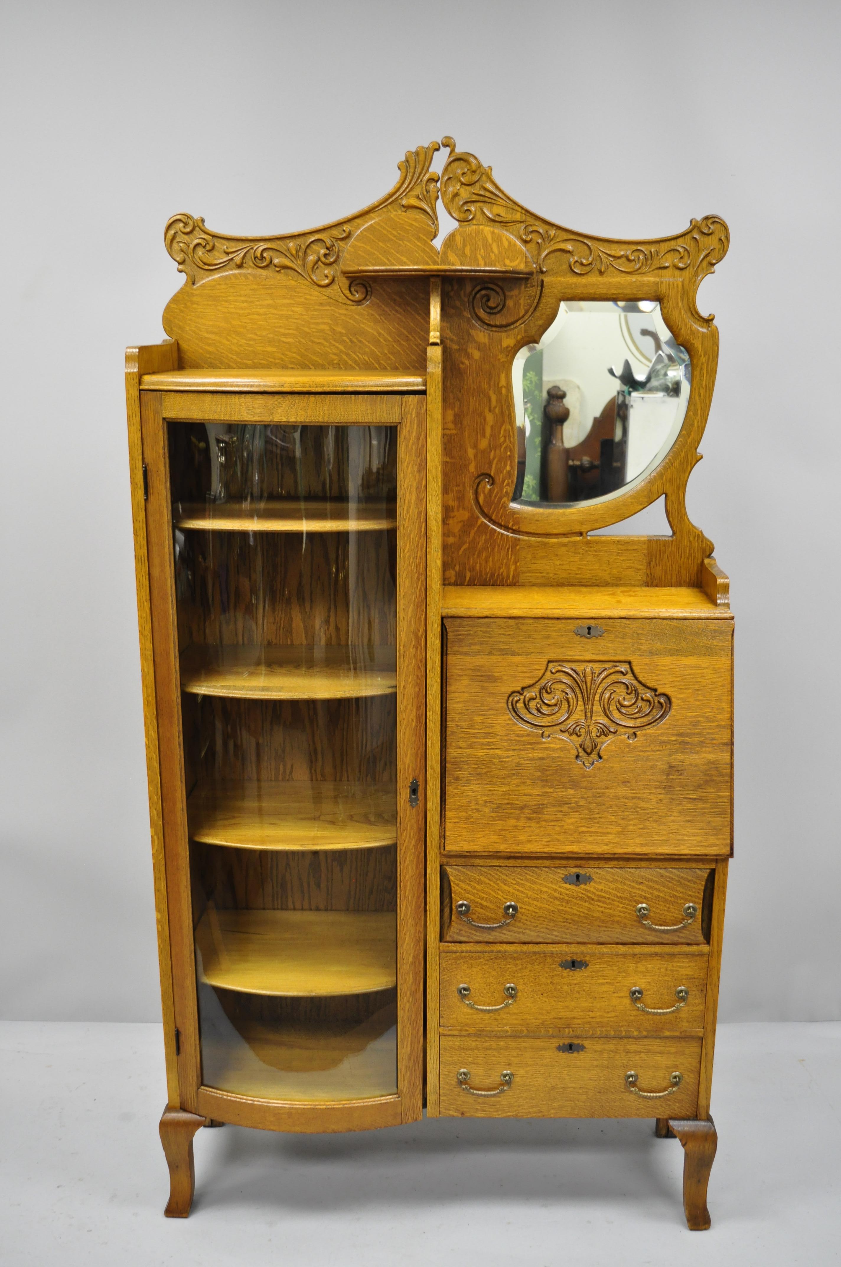 Victorian golden oak side by side bow glass curio secretary desk bookcase. Item features bow glass door, fall front writing surface, solid oakwood construction, nicely carved details, beveled glass mirror, 3 drawers, 4 adjustable shelves. Original