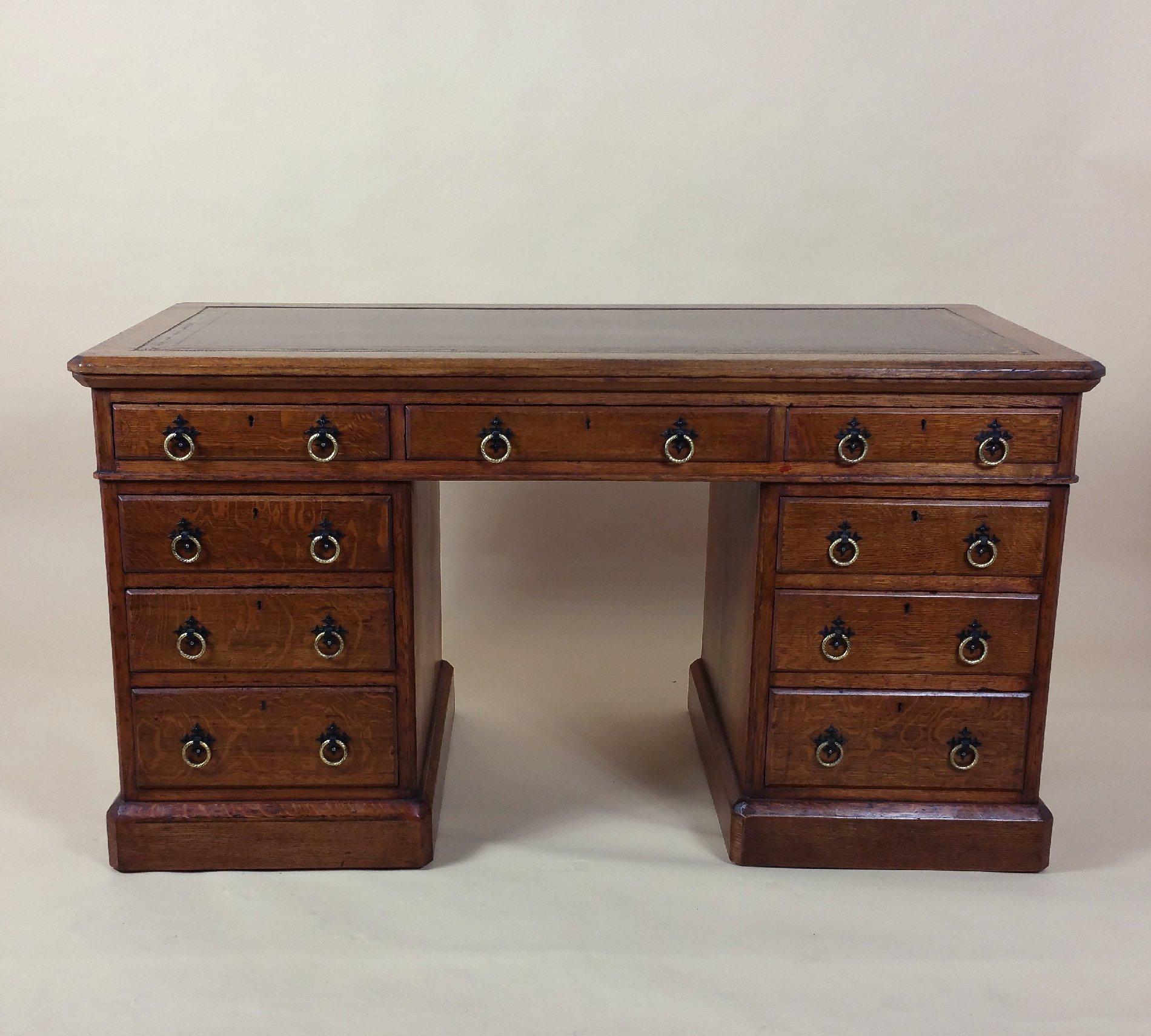 This marvellous and very handsome Victorian Gothic oak pedestal desk features four graduating drawers on either side with a central top drawer, finished with brass and iron designed Gothic pull handles. The desk is English and is topped with deep