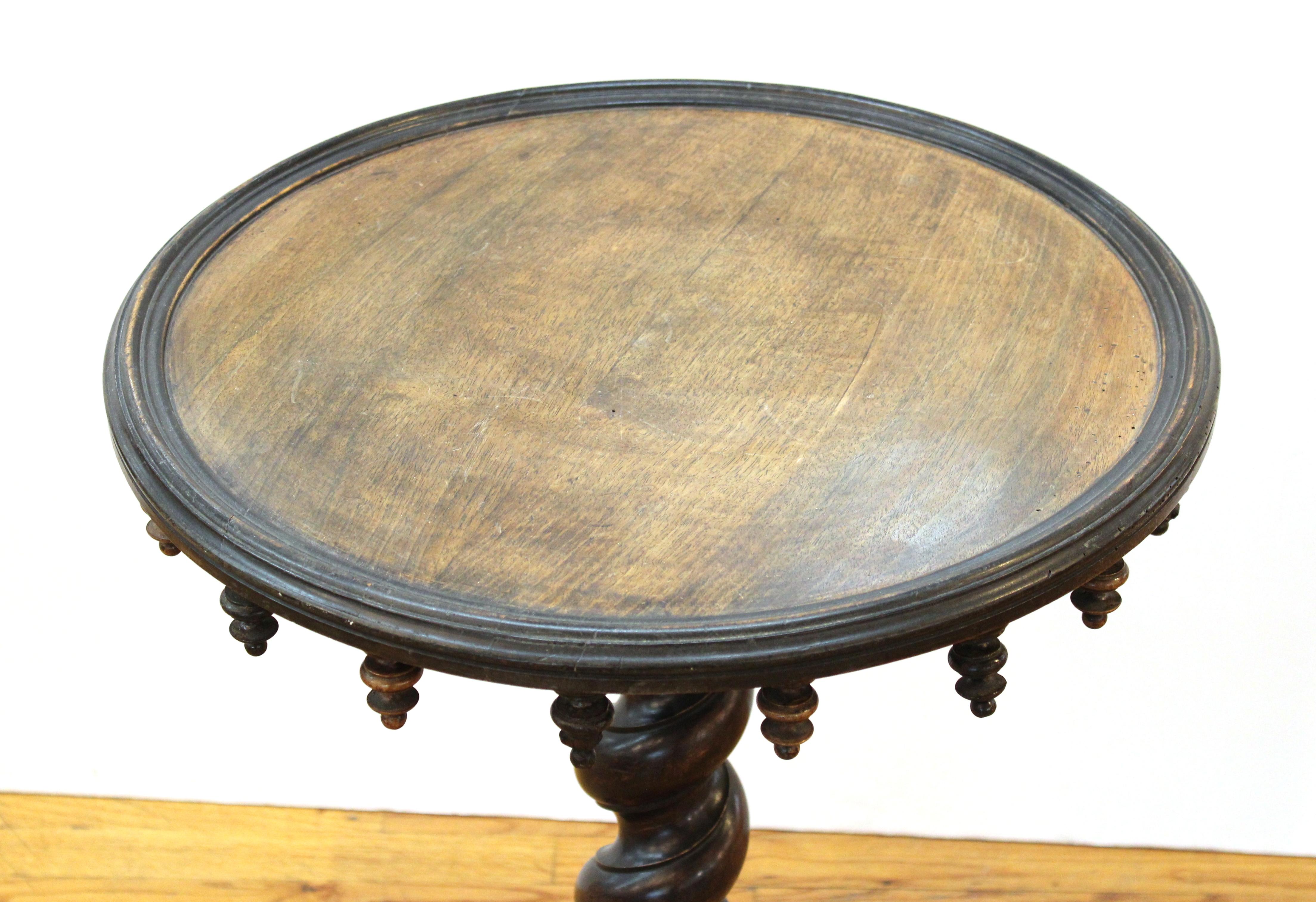 Victorian Gothic Revival mahogany & fruitwood circular center table. The underside of the top rimmed with carved drop pendants, on a barley twist column and bulls eye base. Measures: 31.5
